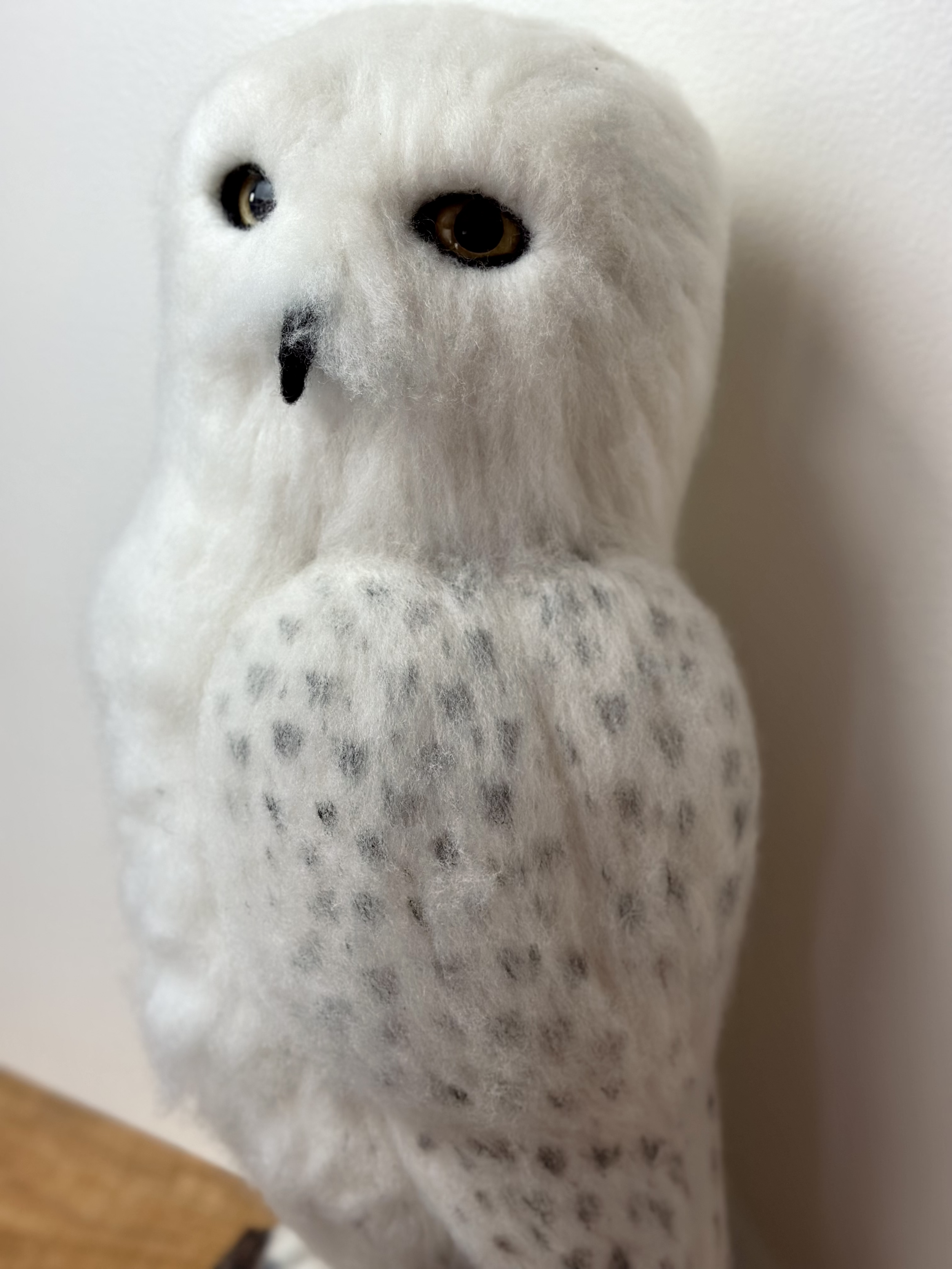 Life Size Snow Owl, handmade with Merino and Corriedale wool, perched on a log.