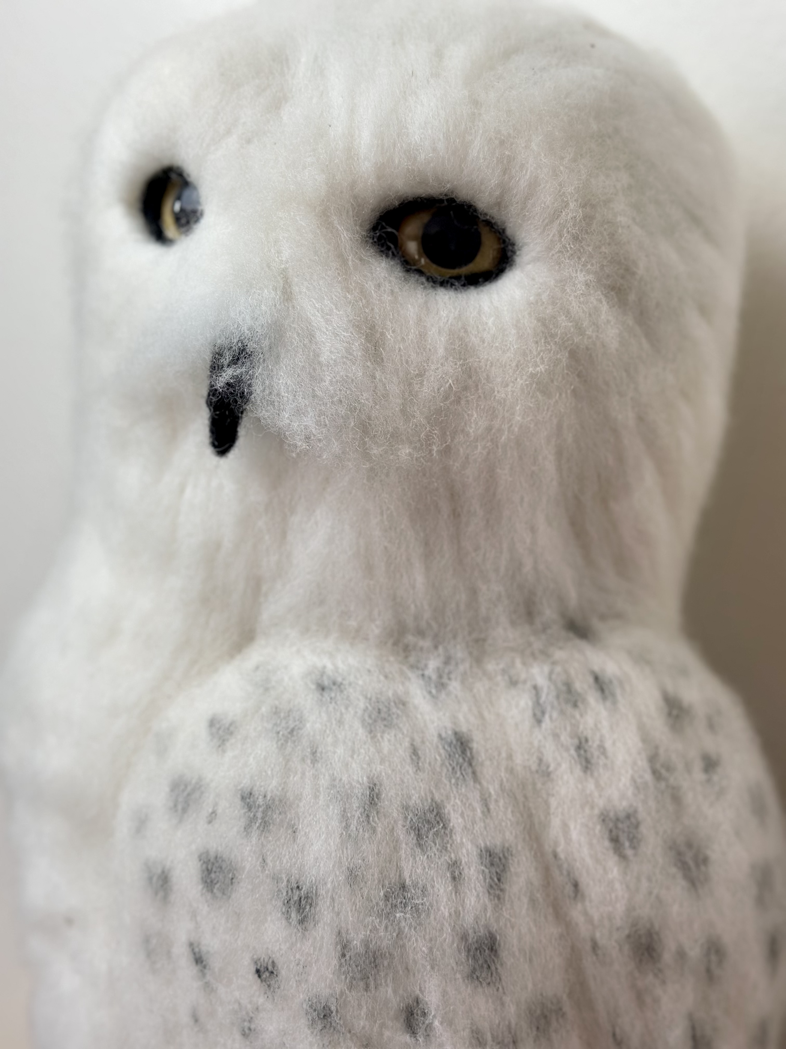 Life Size Snow Owl, handmade with Merino and Corriedale wool, perched on a log.