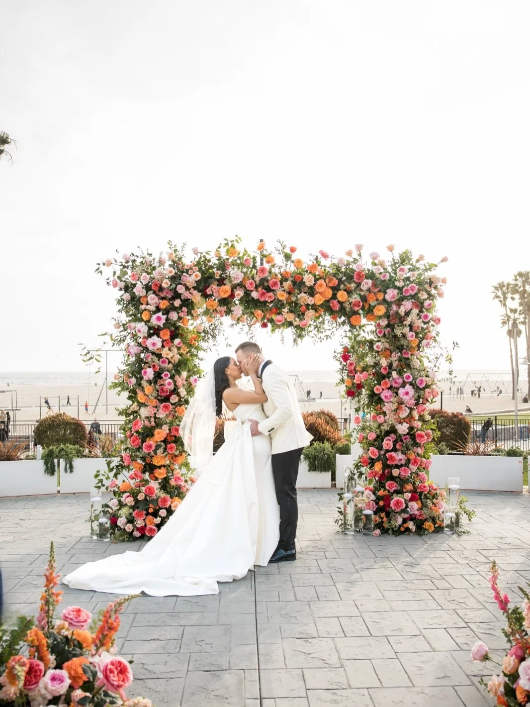 A touch of vibrant florals against a neutral backdrop transforms your ceremony by Pacific Ocean at the Regent Hotel in Santa Monica into a breathtaking celebration of love. Soft petals, elegant arrangements, and pops of color bring warmth and life to