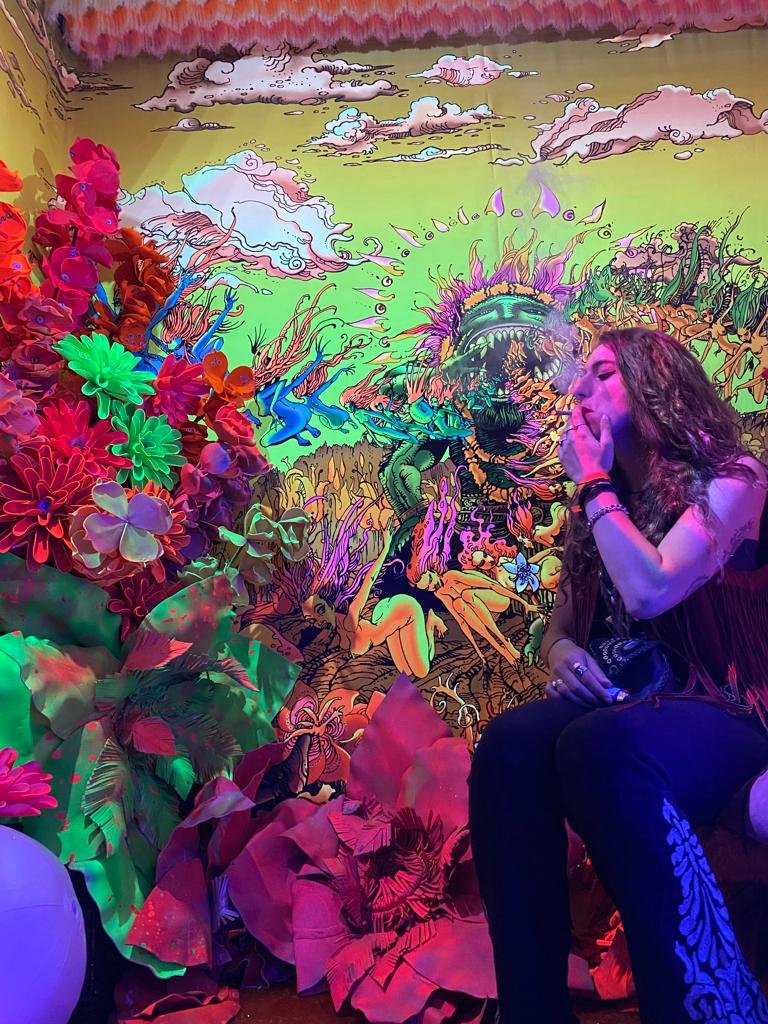 Alice fumando um beck com fundo colorido