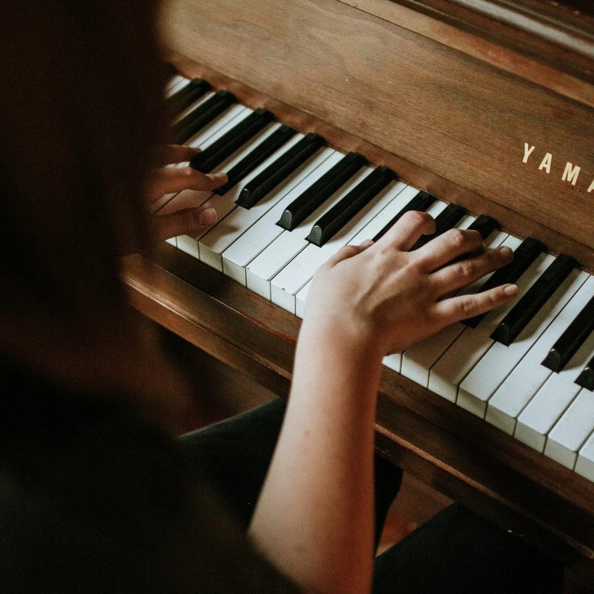 Child's hands playing an upright piano.jpg