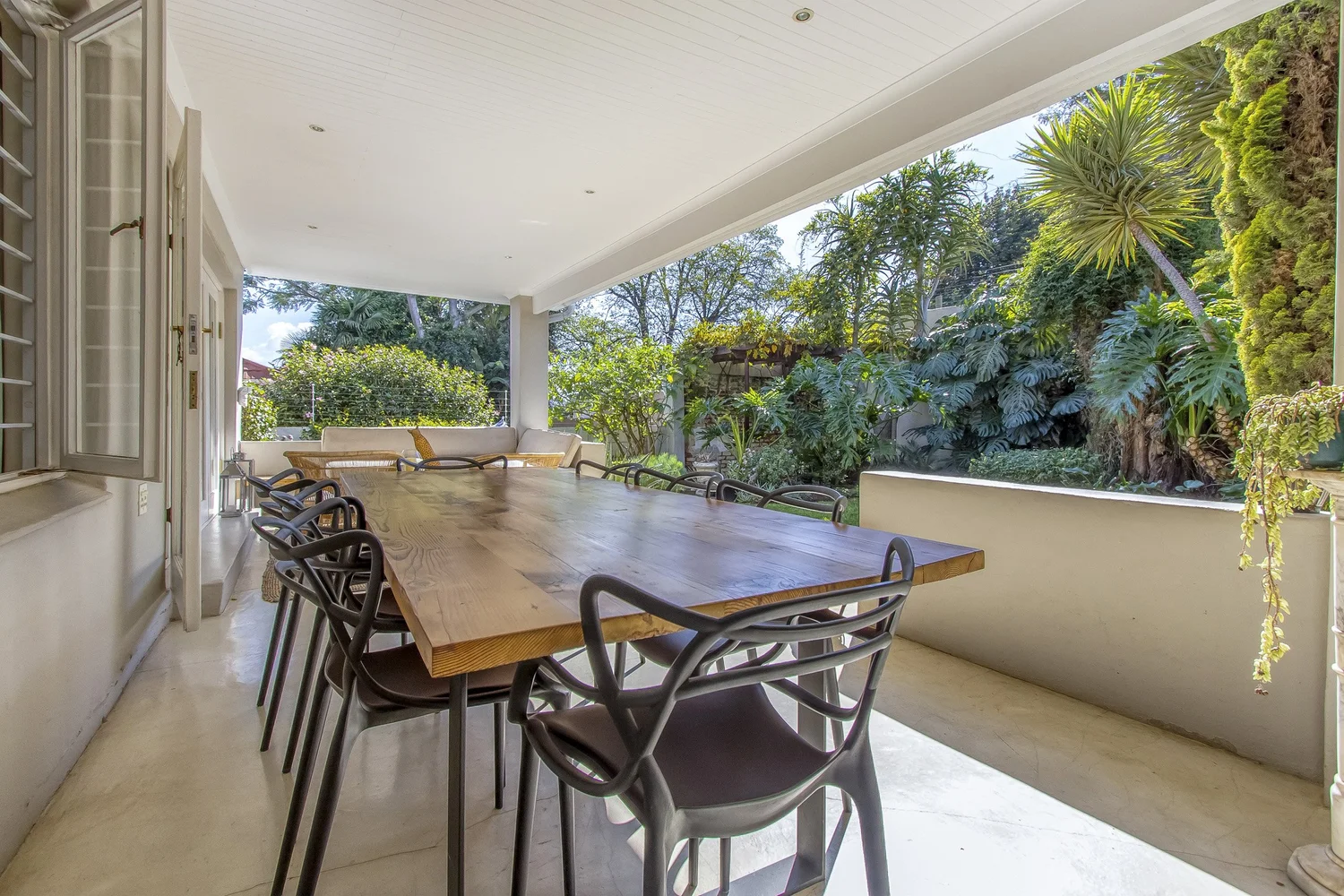 Long dining table on the covered veranda beside the garden