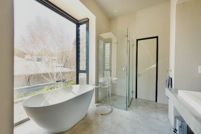 Ensuite with freestanding bath beside a large window onto the treetops