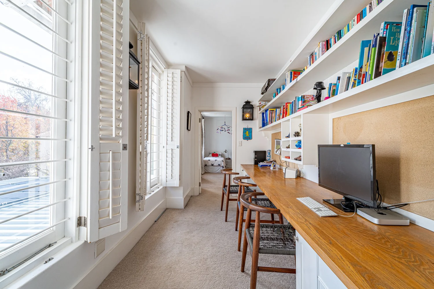 Long built-in study desk with bookshelves and leafy views