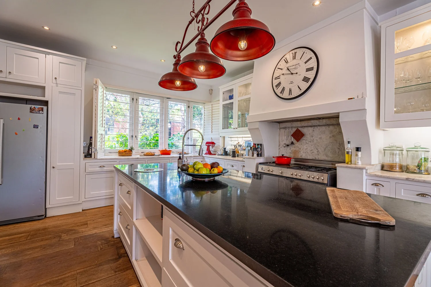 Cottage-style kitchen with red pendant lights and glass-fronted cabinetry