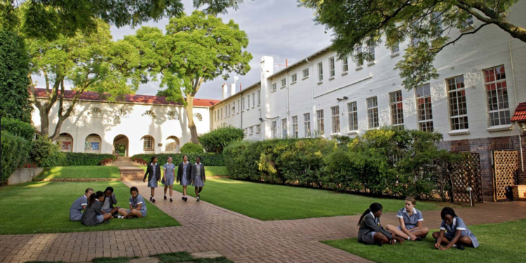 Pupils sitting on the lawn in a courtyard at St Mary's School, Waverley