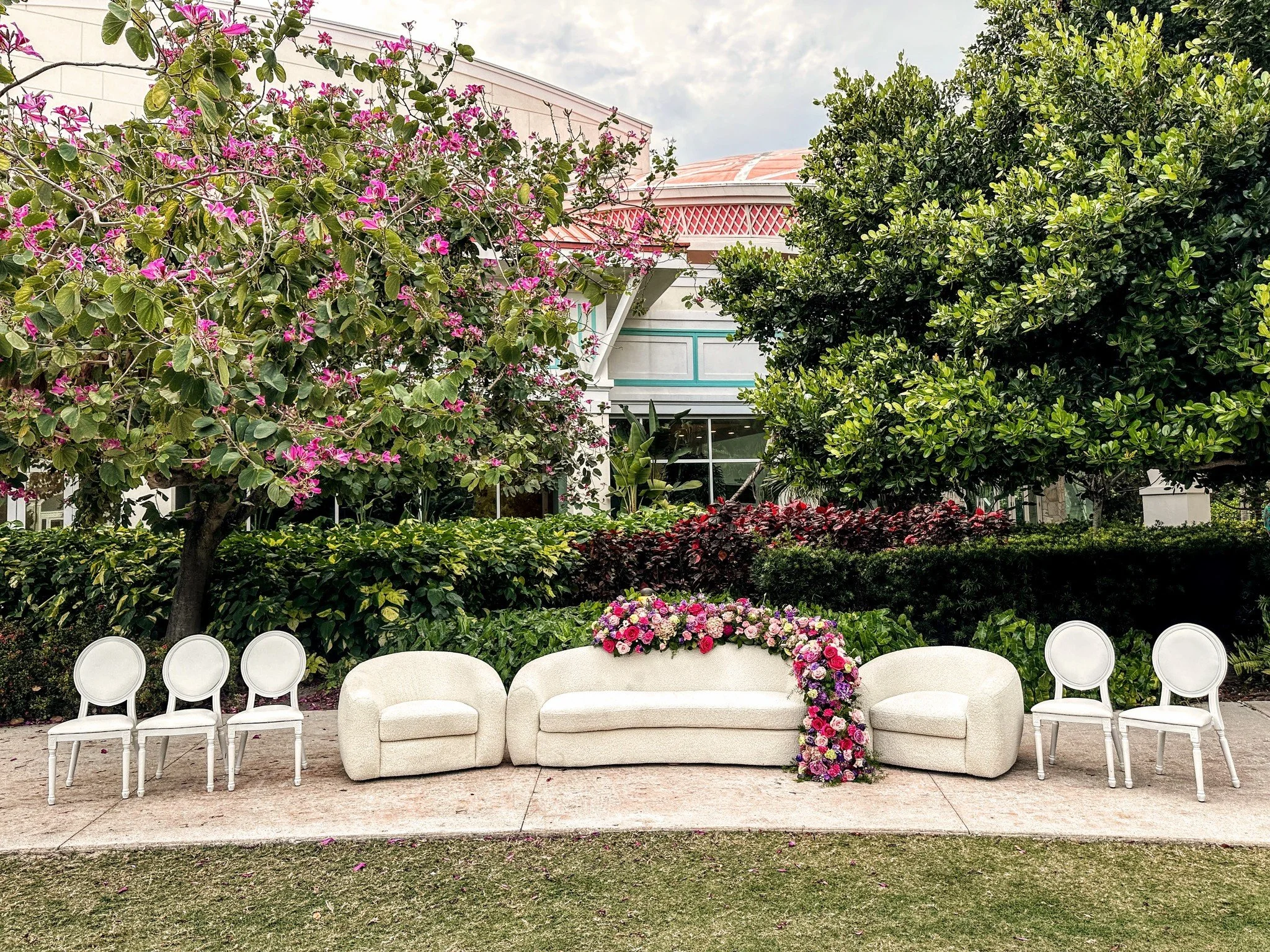 A quiet seat for two, waiting in the shade just beyond the lawn &mdash; a space to pause together before the vows, wrapped in florals and stillness.

Nearby, the ceremony arch rose with soft structure and purpose, gently framing the moment to come.

