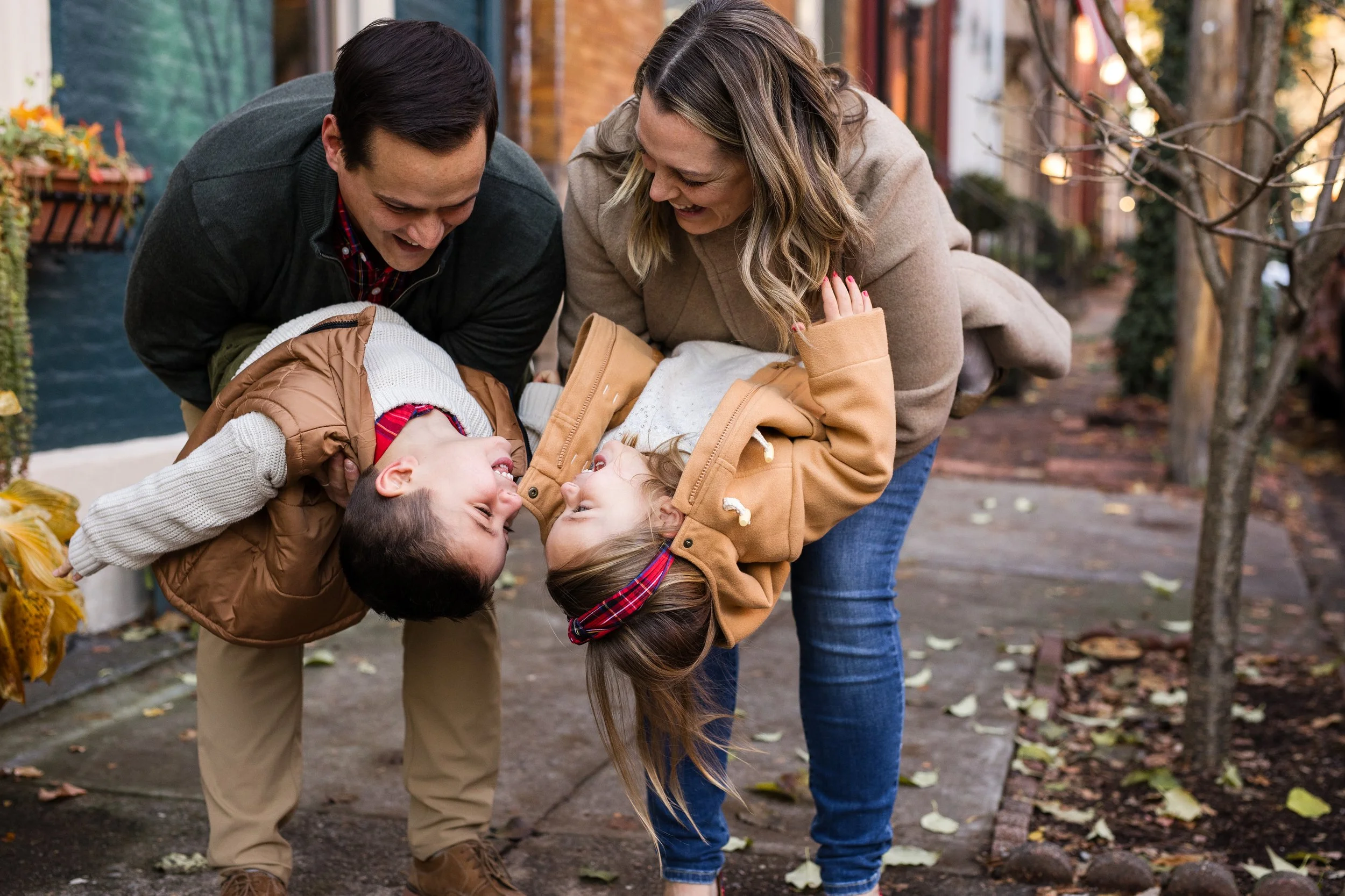 Parents hold their kids upside down, who laugh at each other