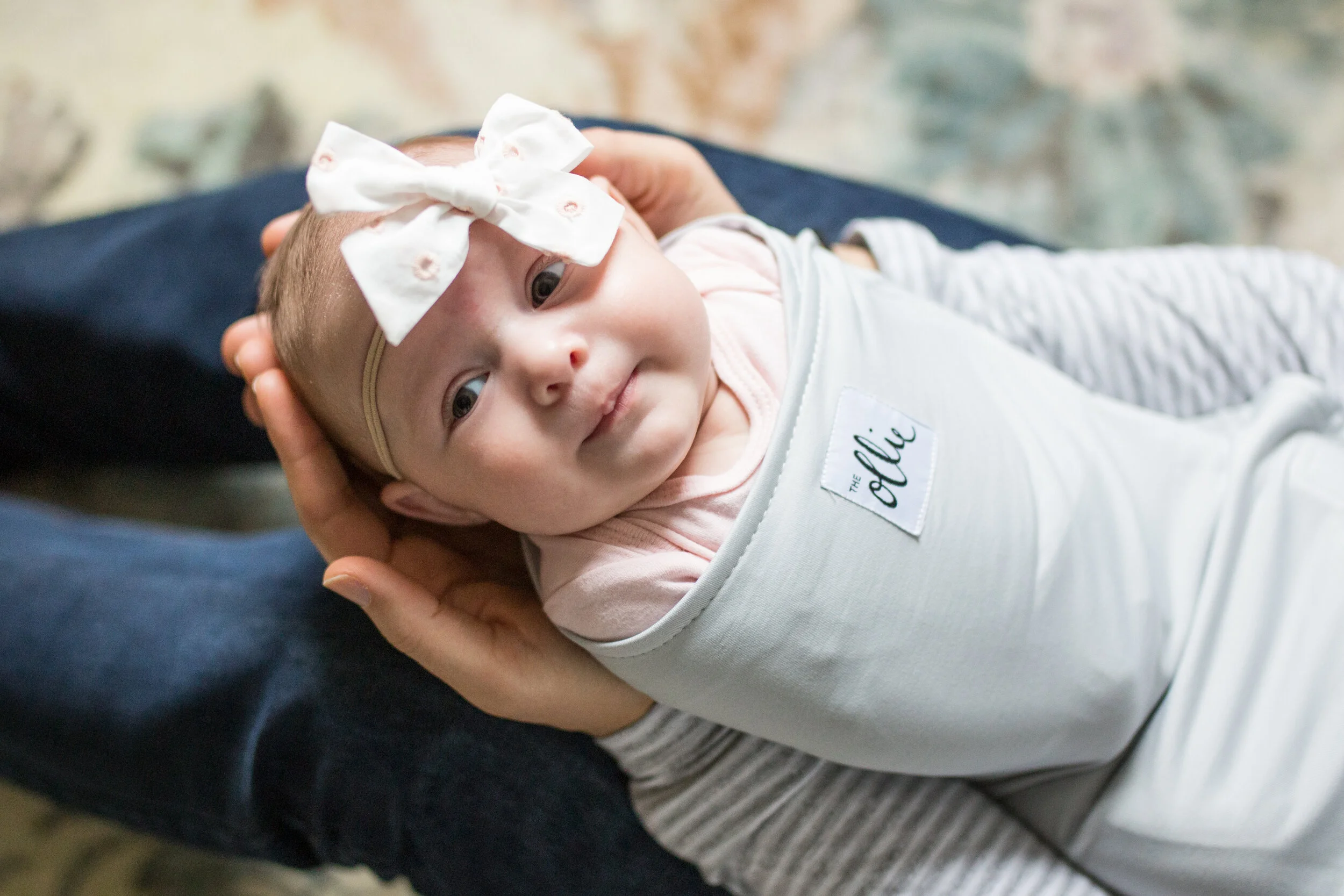 A swaddled baby smiles while being held by her father