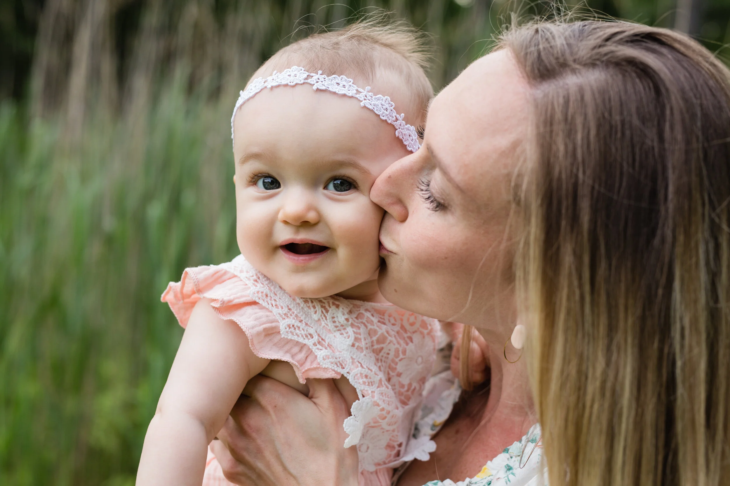 A mom kisses the cheek of her baby girl
