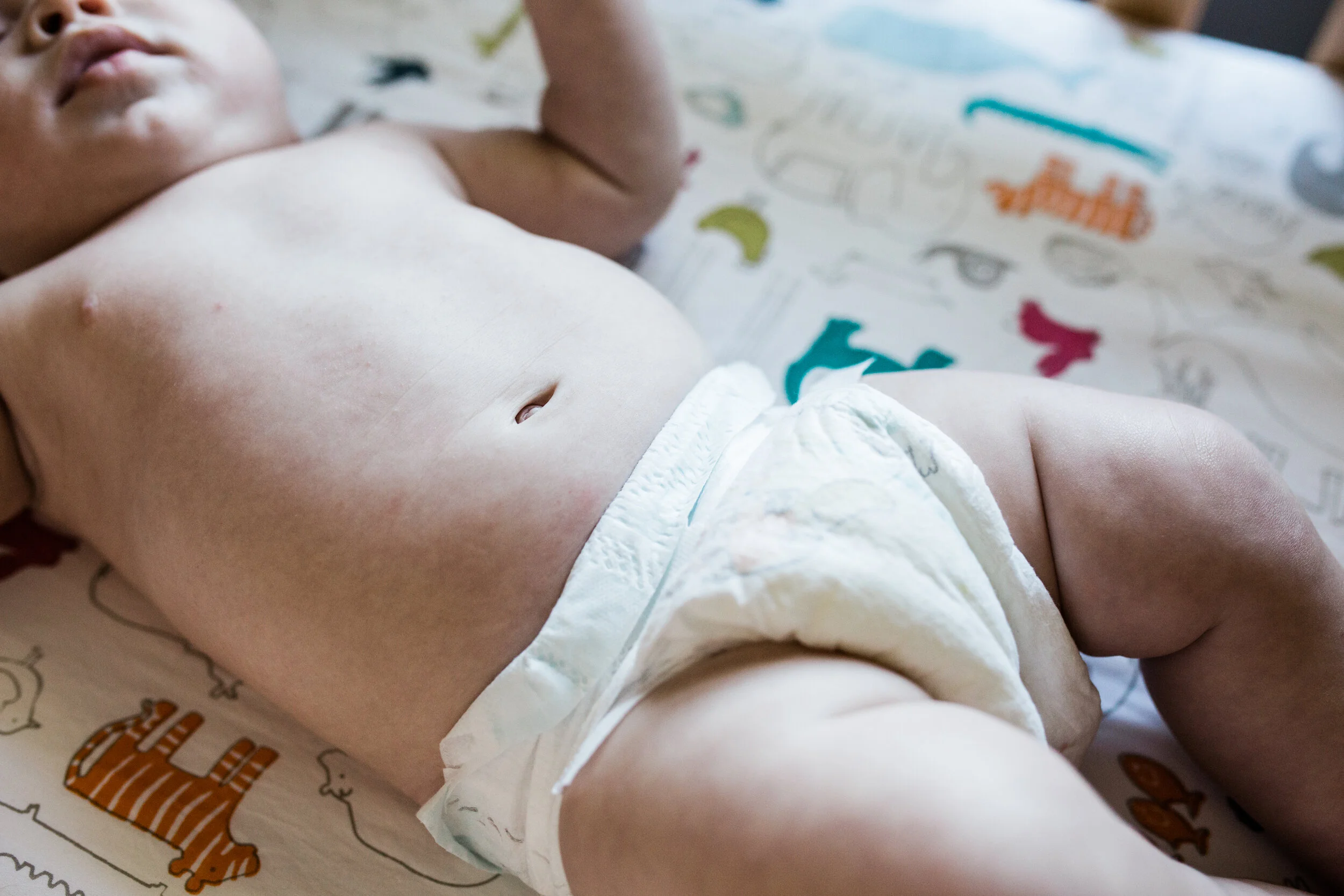 A closeup of a baby’s belly button, laying in his crib