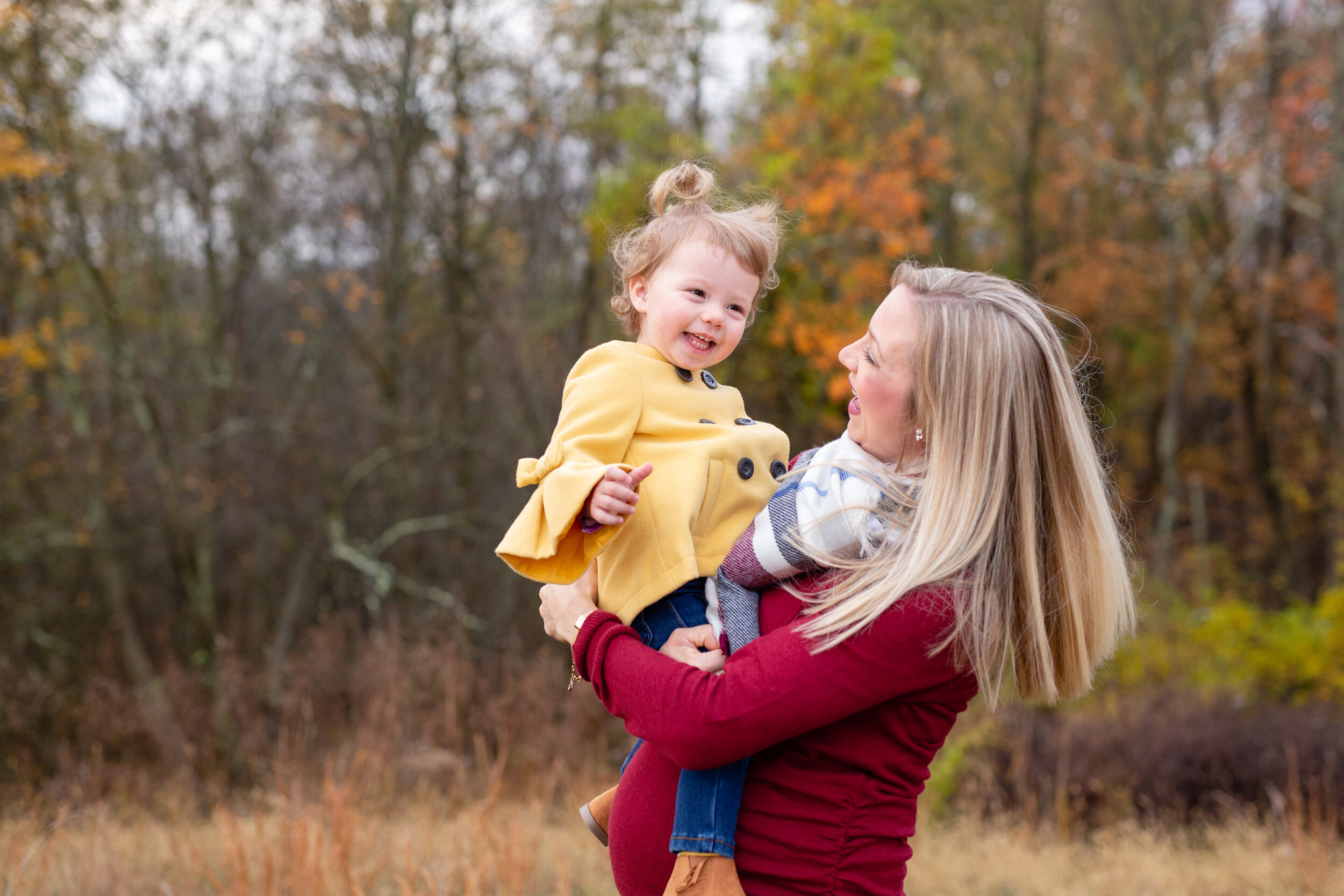 A pregnant mom swings her daughter around in the air. The child laughs