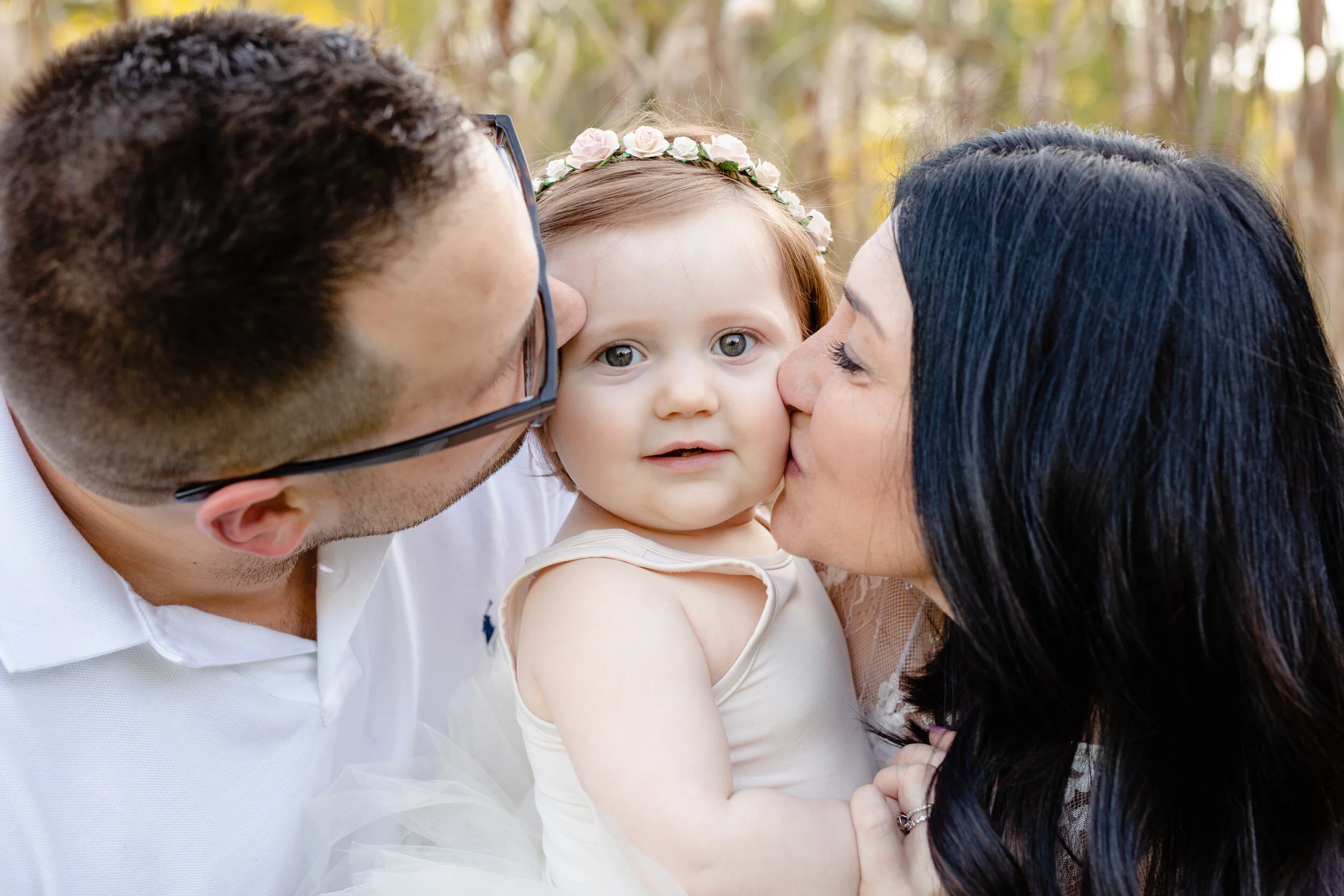 Parents kiss the cheeks of their daughter
