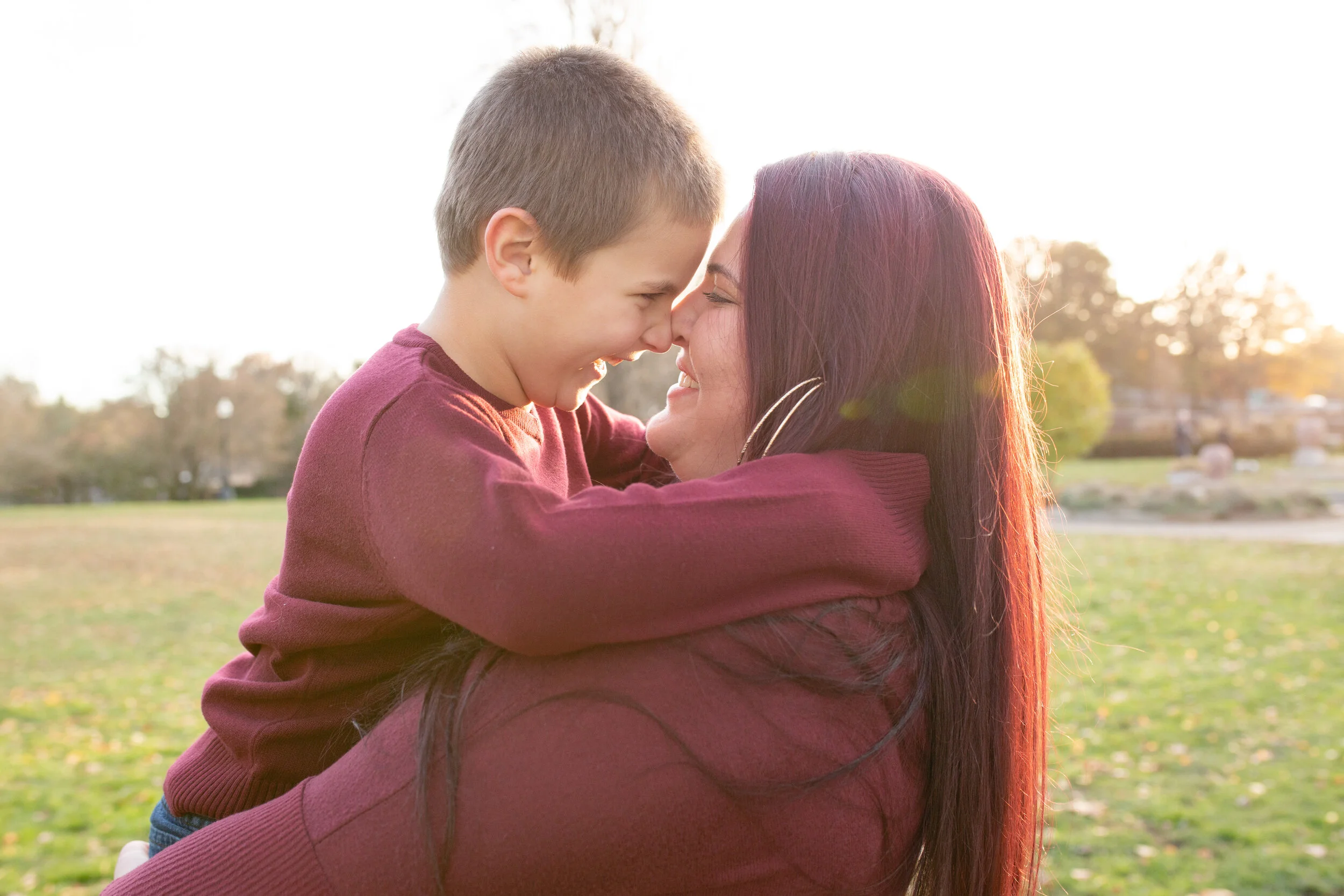 A young boy touches noses with his mom as they both smile and laugh