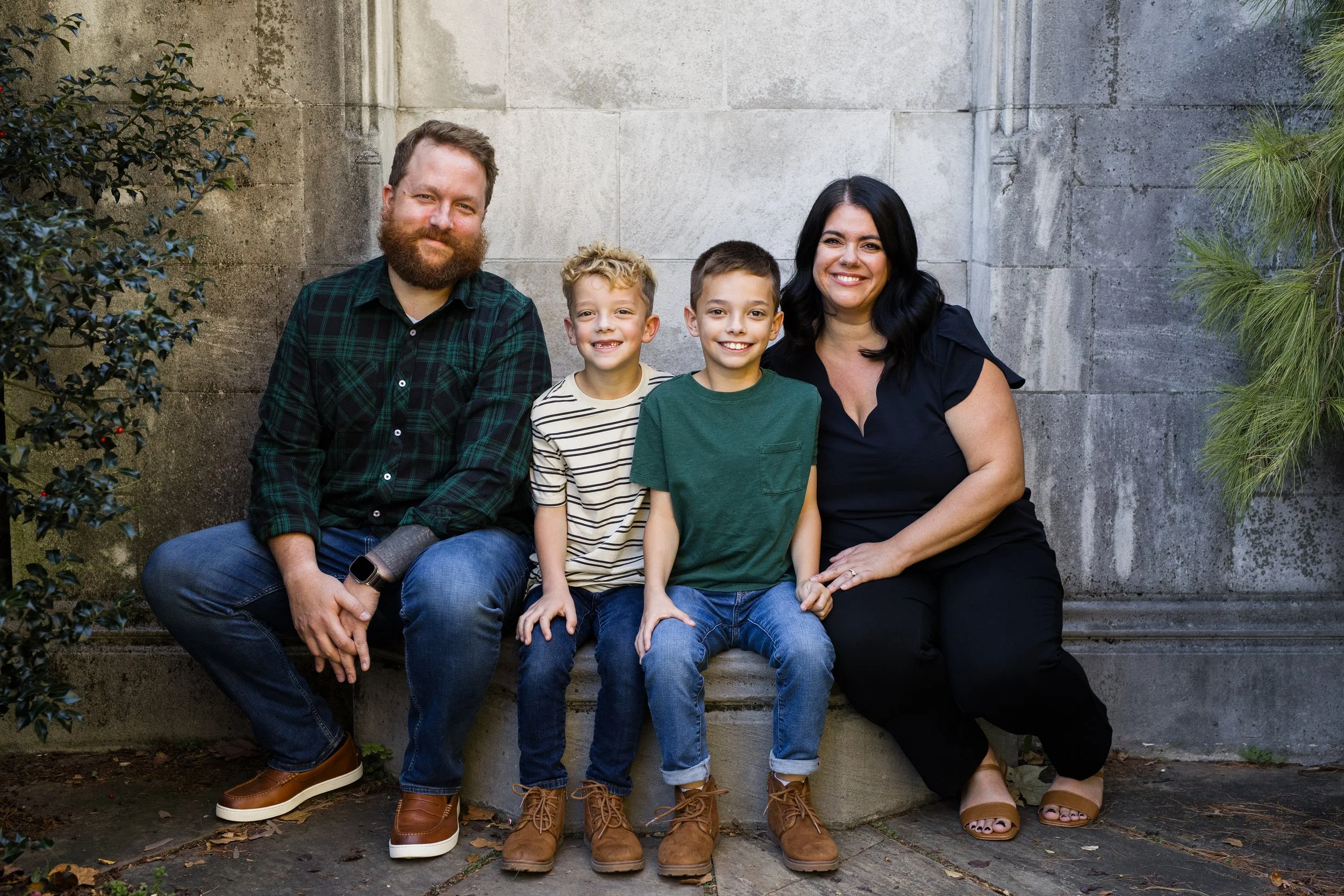 Parents and their two sons sit on a stoop at Mellon Park and smile