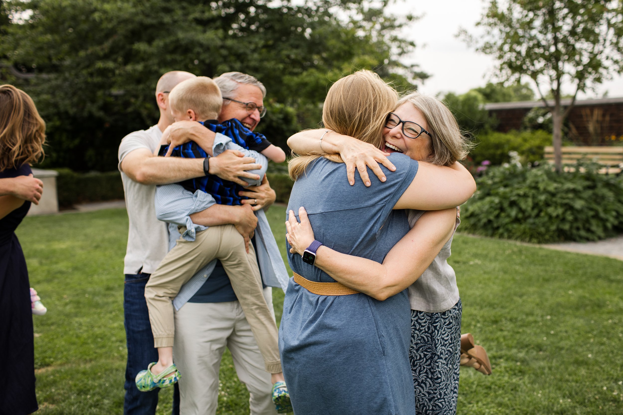 Extended family joyfully hug one another at Mellon Park
