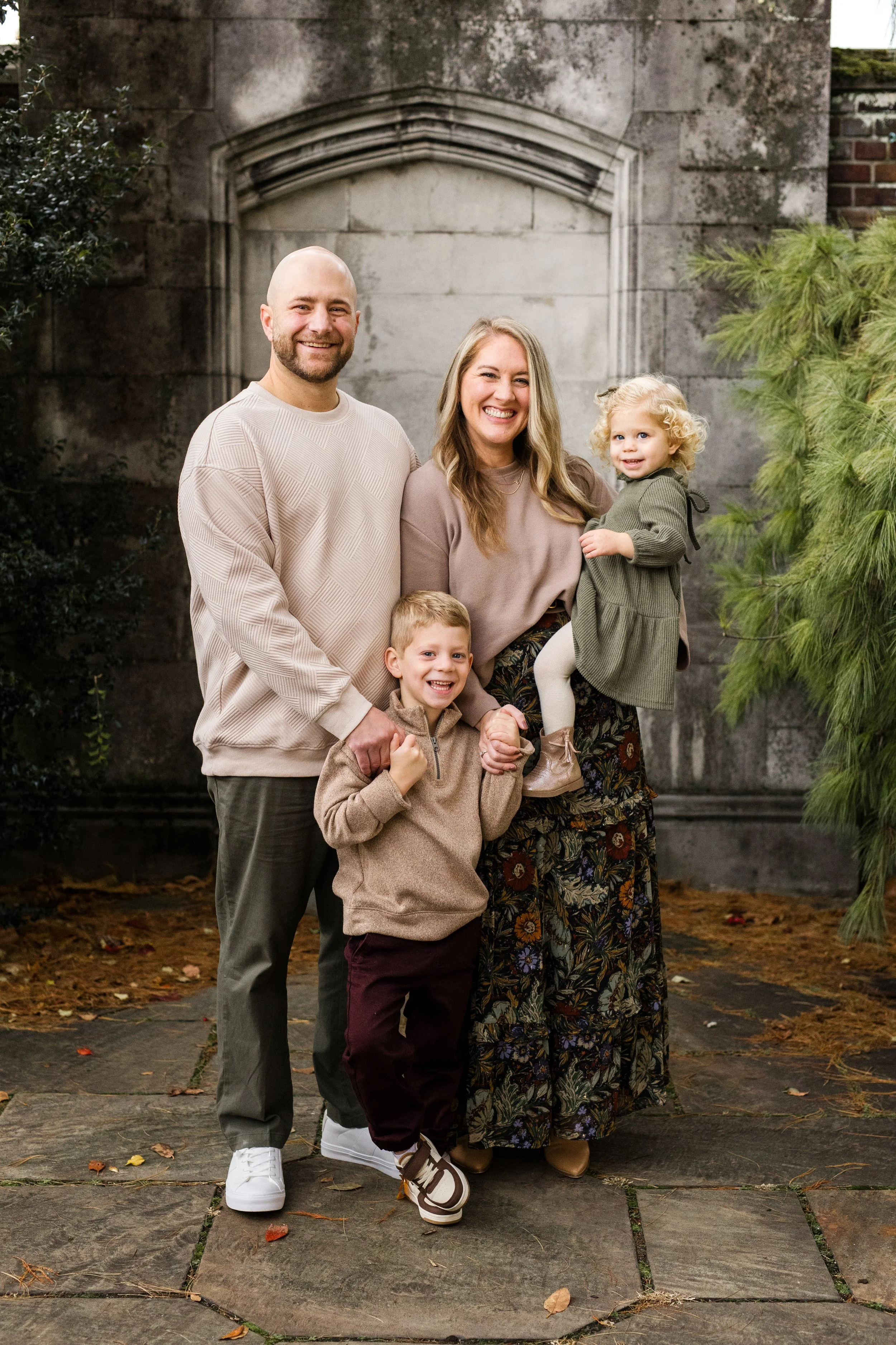 A family stands in front of an iconic photog backdrop in Pittsburgh's Mellon Park. Everyone is smiling big and looking at the camera.