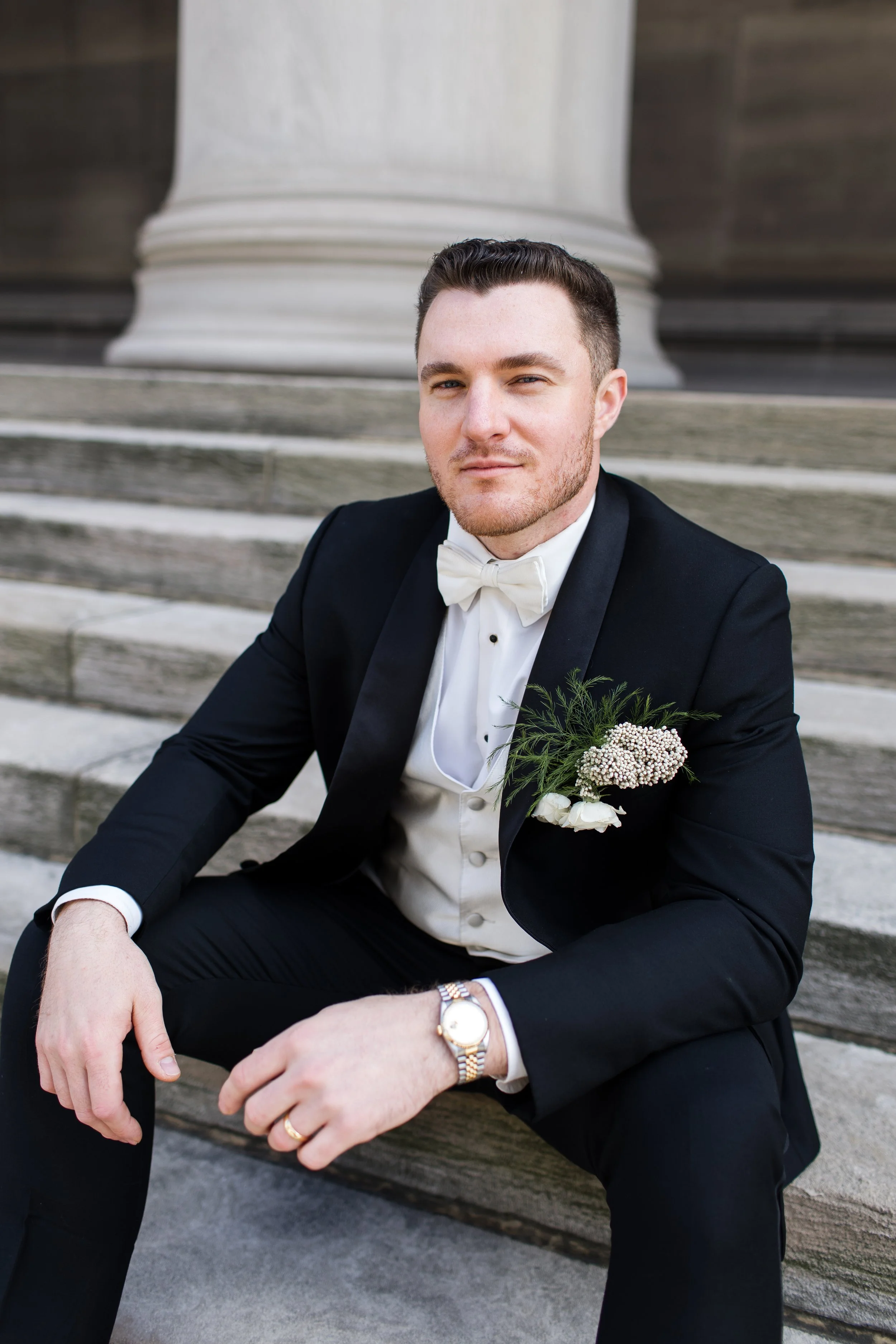 A groom sits on the steps of the Mellon Institute, a sly smile on his face.
