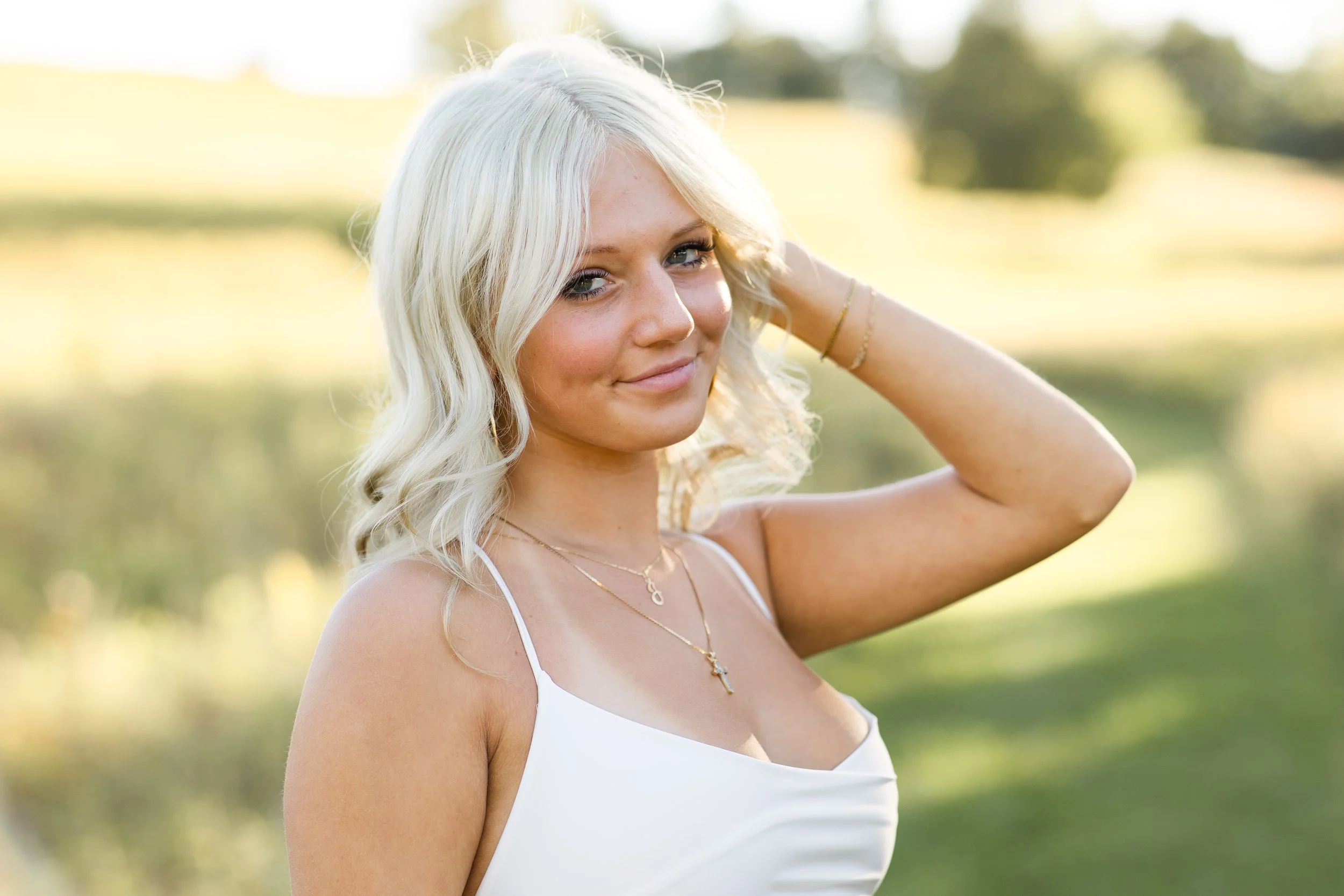 Pittsburgh Senior plays with her blonde hair as she walks through a field.