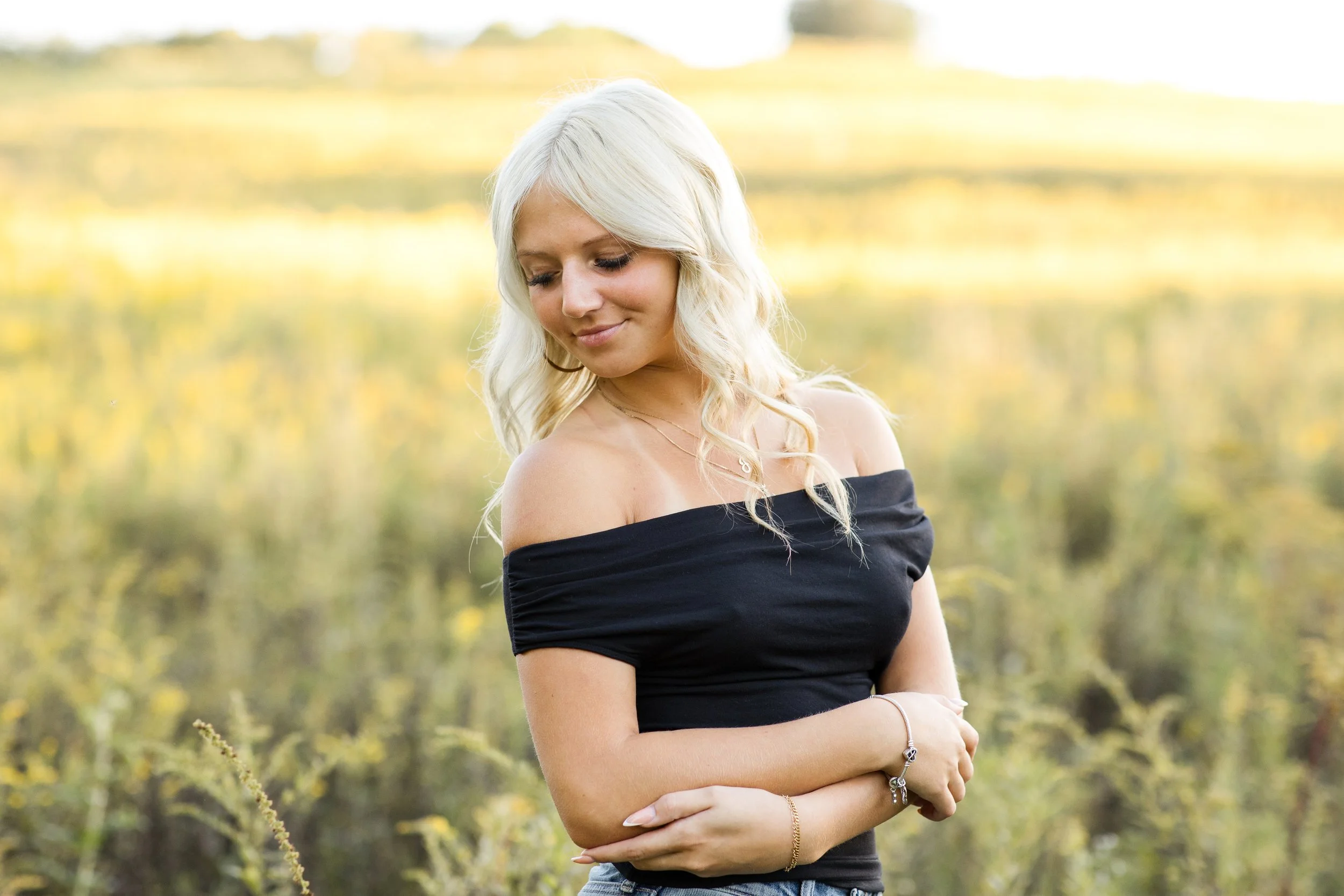 Senior girl looks over her shoulder as she walks through a field