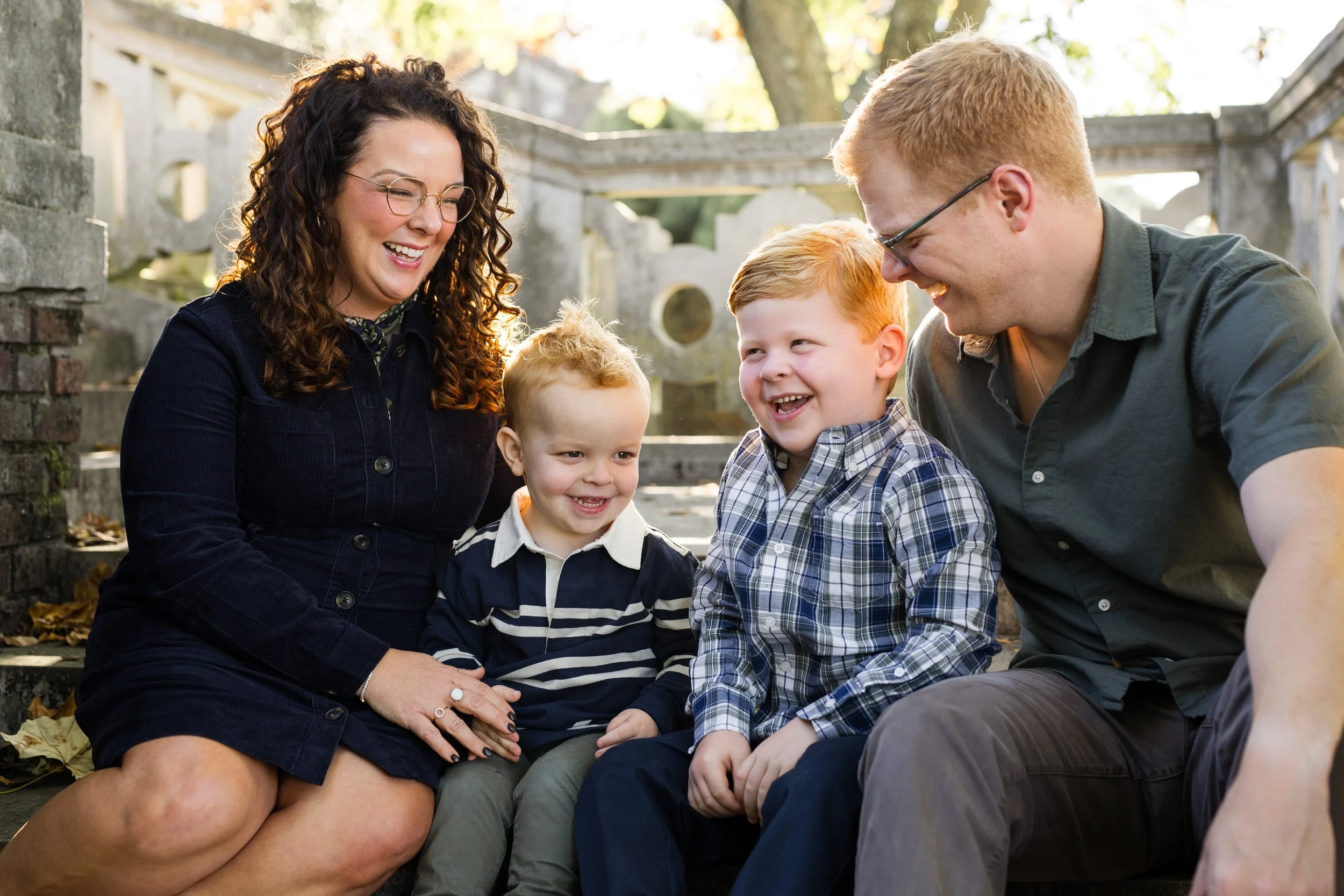 A family laughs together sitting on the stone steps at Mellon Park