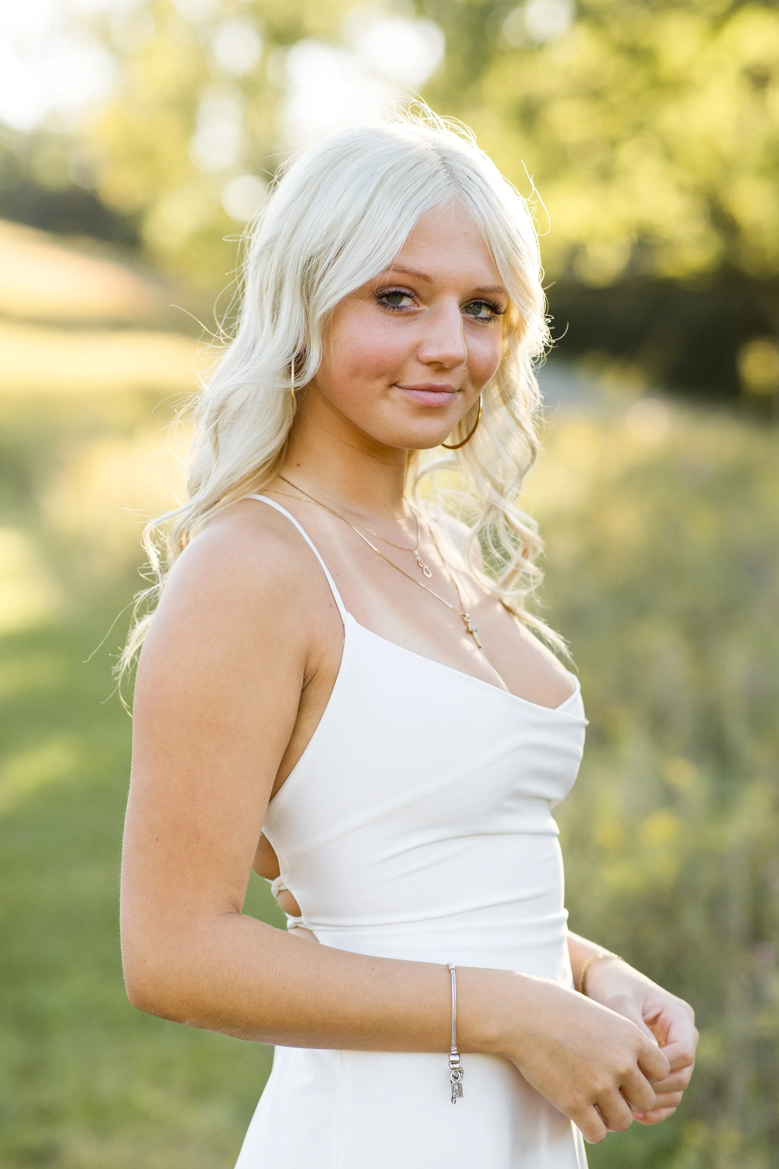 Gorgeous Pittsburgh Senior, Jersie, models a white dress in a beautiful field