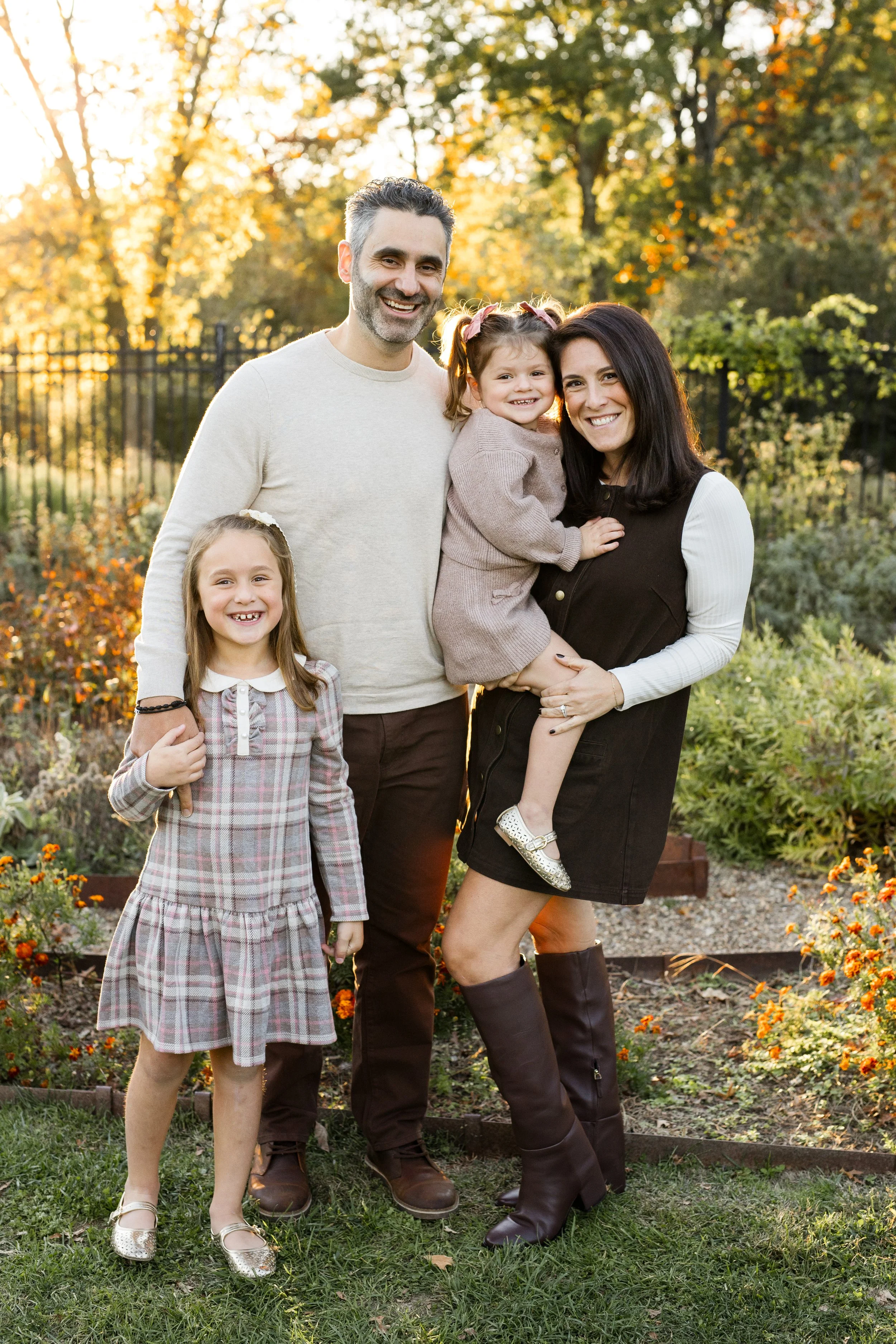 A family stands in a garden with the sun shining behind them.