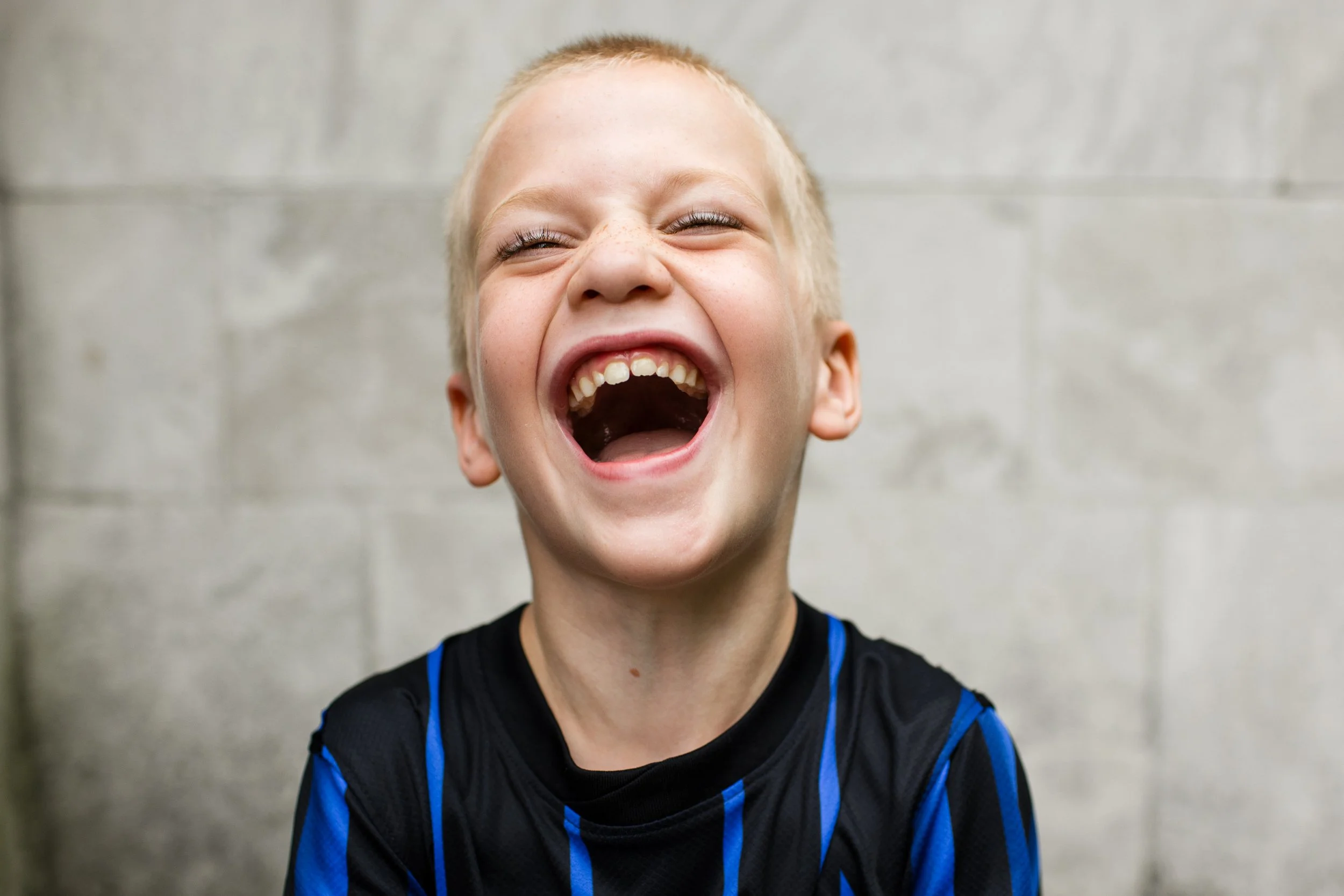 A boy laughs joyfully for a portrait in Pittsburgh