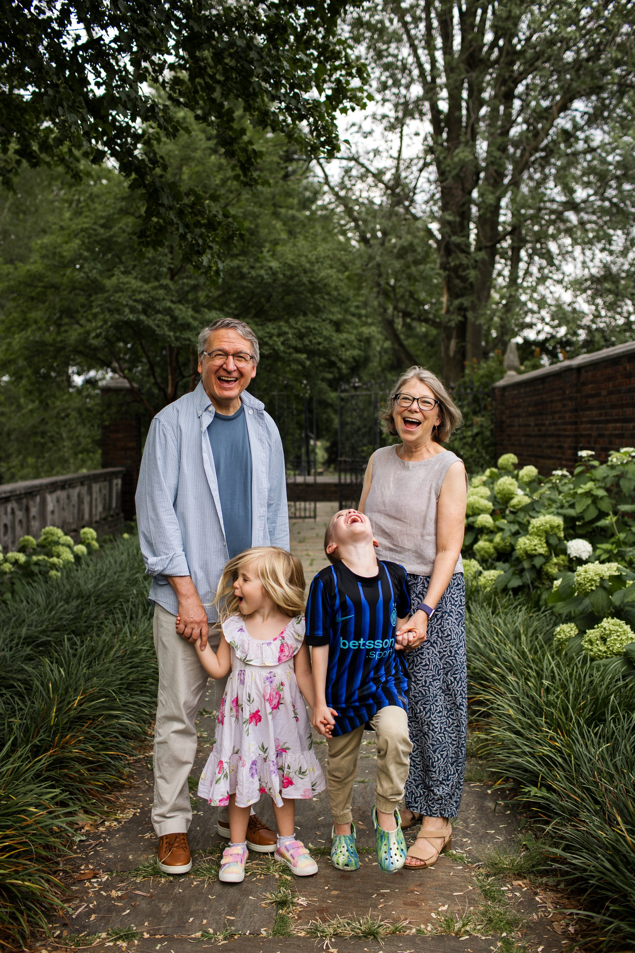 Grandparents laugh alongside their grandkids at Mellon Park during an extended family photo session with multiple generations