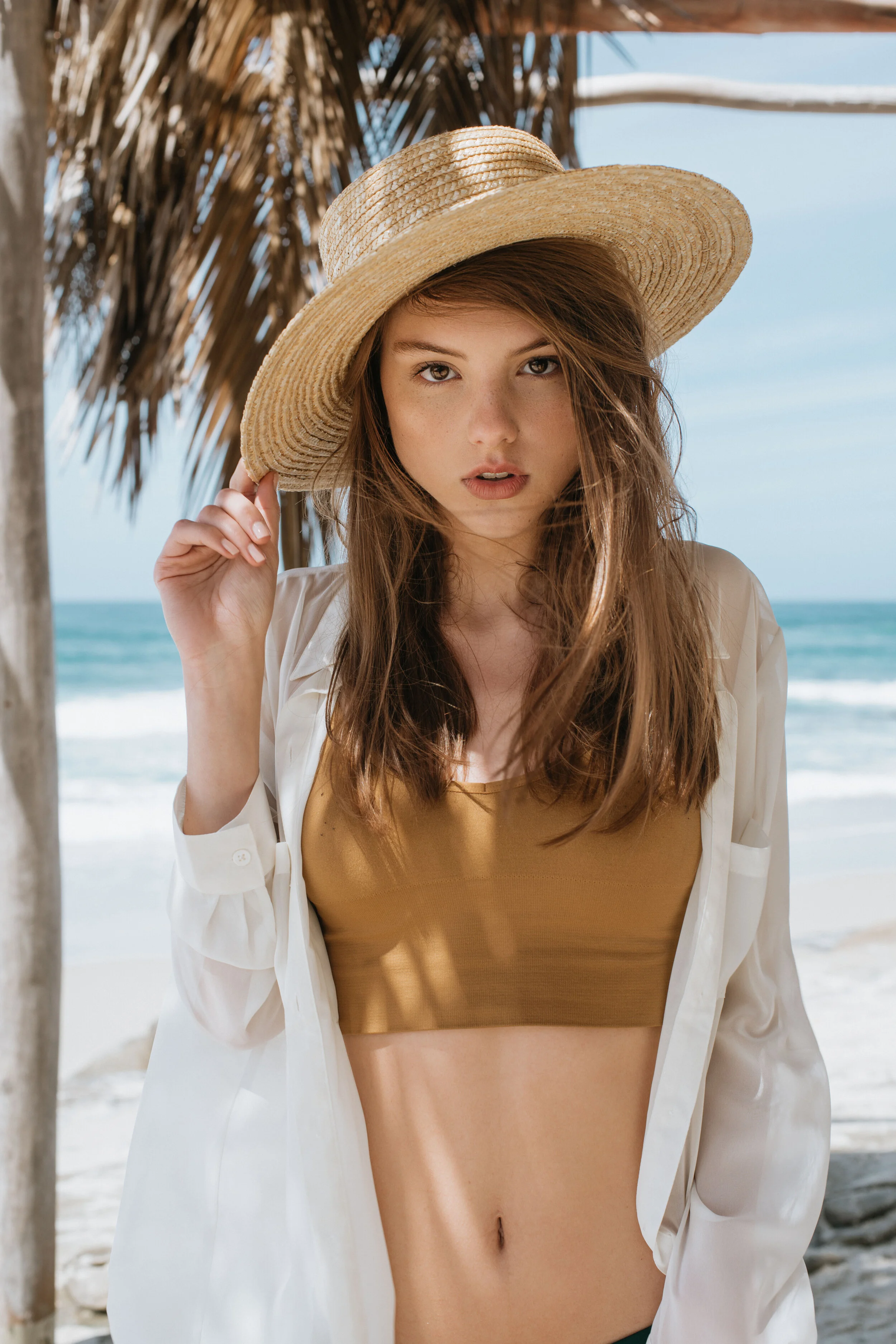  Beachside fashion portrait of model in straw hat and amber swimsuit with white cover-up on the california coast 
