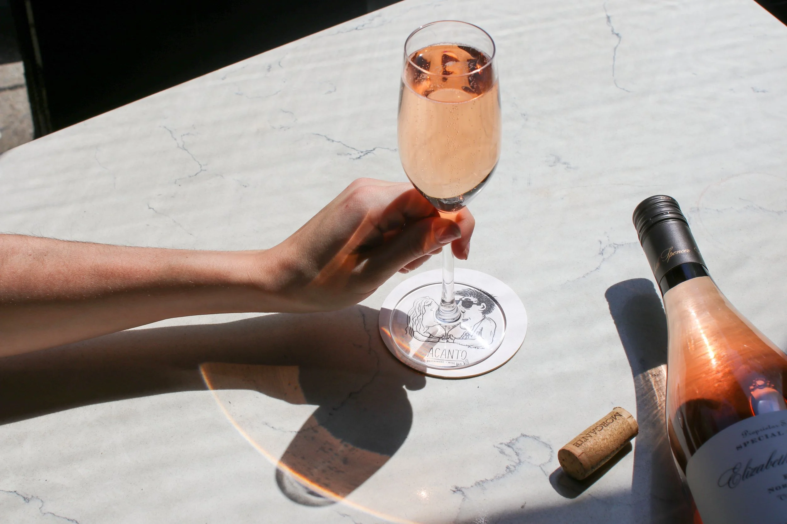 Rose wine on marble table with hand grabbing it