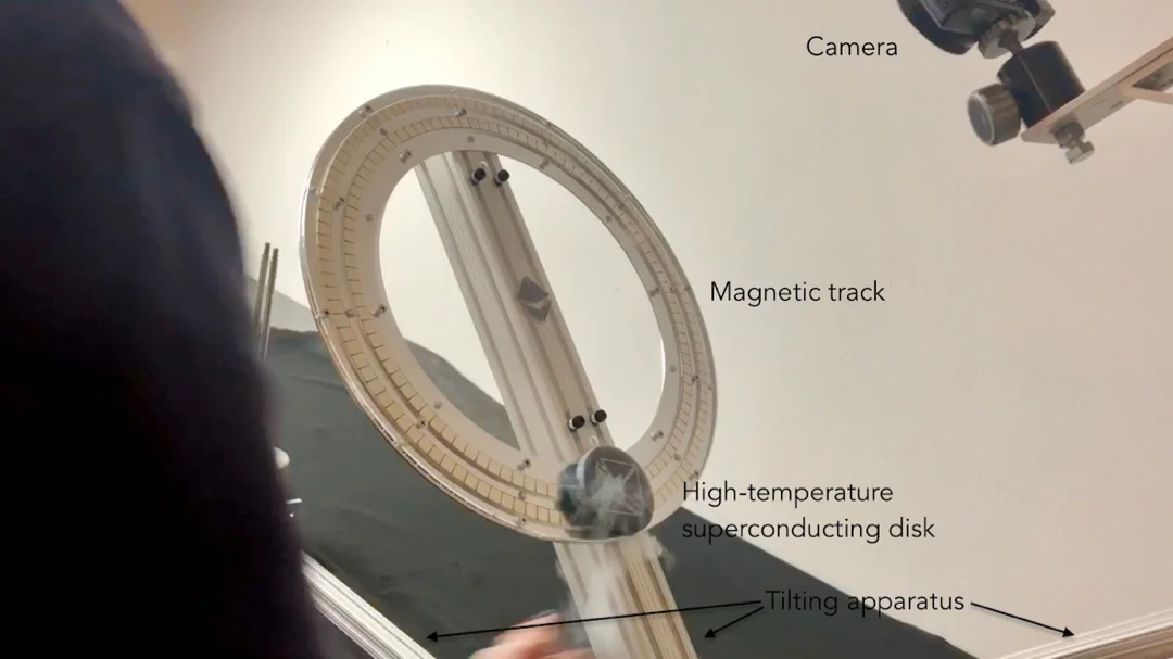 A levitated puck swings nearly frictionlessly from a tilted circular track.