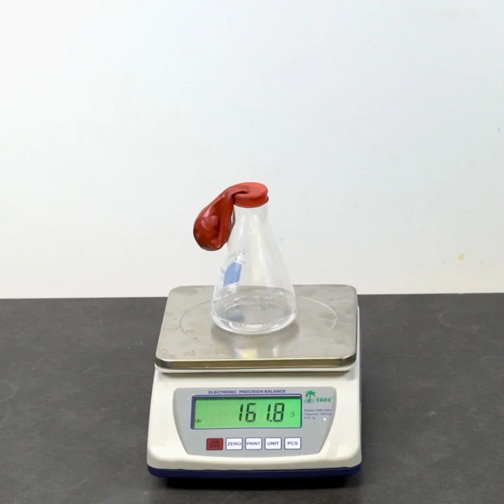 Vinegar is placed in a flask, and sealed with a balloon containing baking soda.