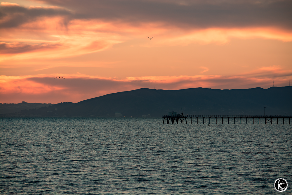 ManuOkai Photography Fire In The Sky sunset over the ocean with pier