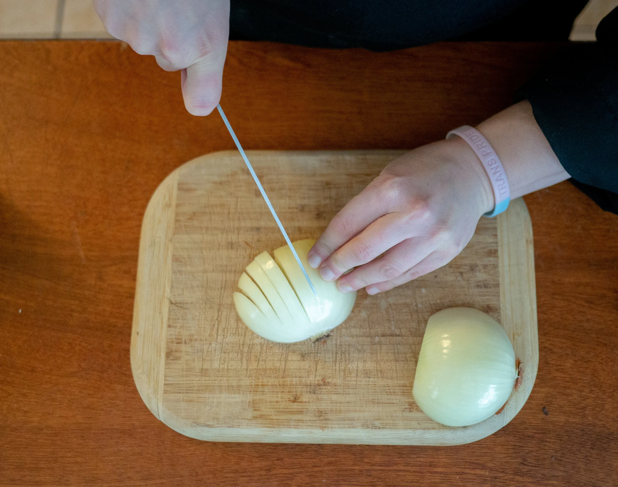 someone cutting an onion on a cutting board