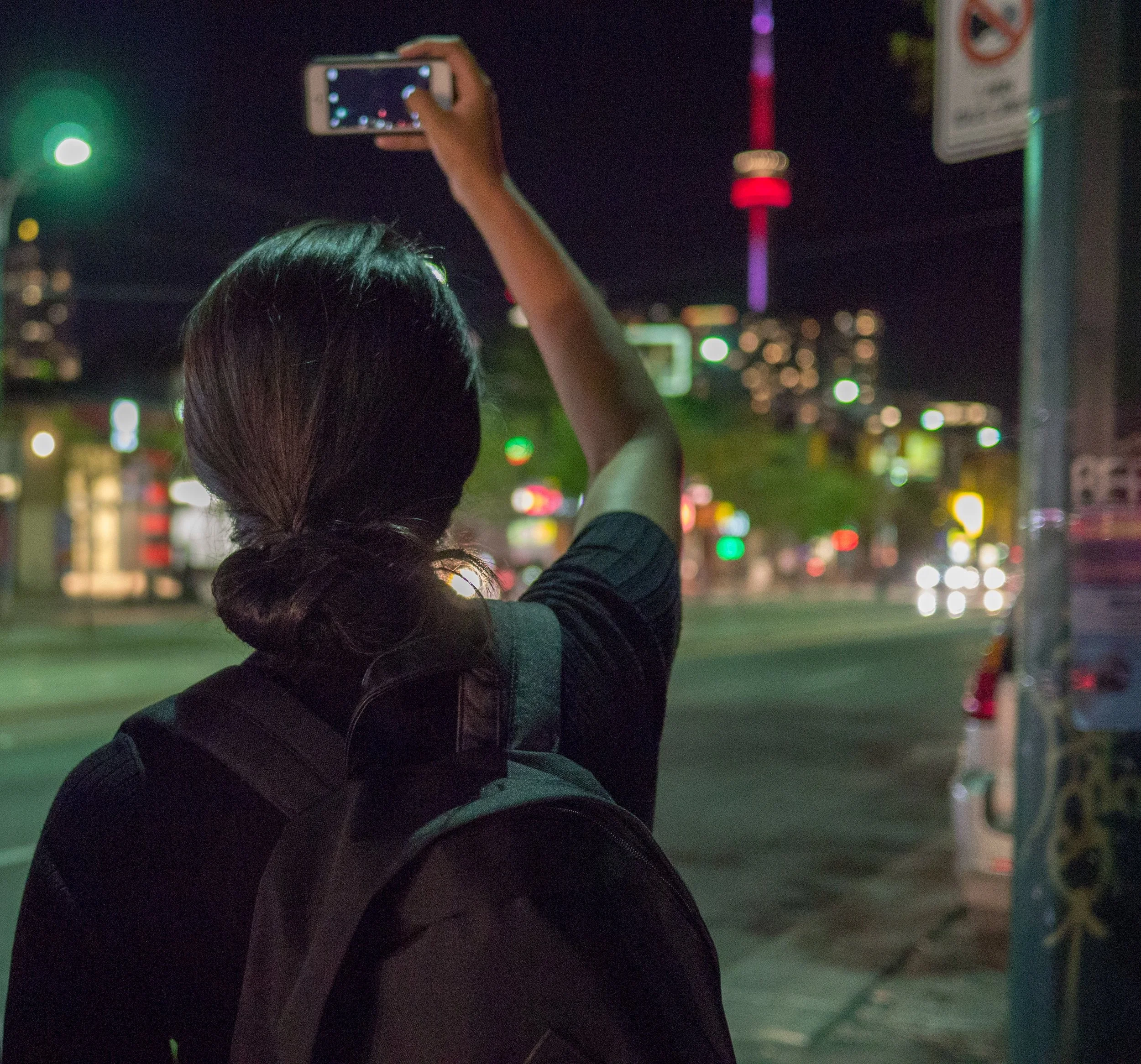 Woman taking photo of CN Tower in Toronto, ON