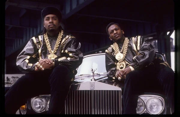 Eric B. and Rakim in a behind-the-scenes shot from their music video for “Follow the Leader,” in the late ’80s, wearing logo’d designs by Dapper Dan.