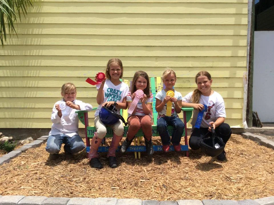 The girls showing off their ribbons on the friendship bench. Everyone is a winner at our farm!