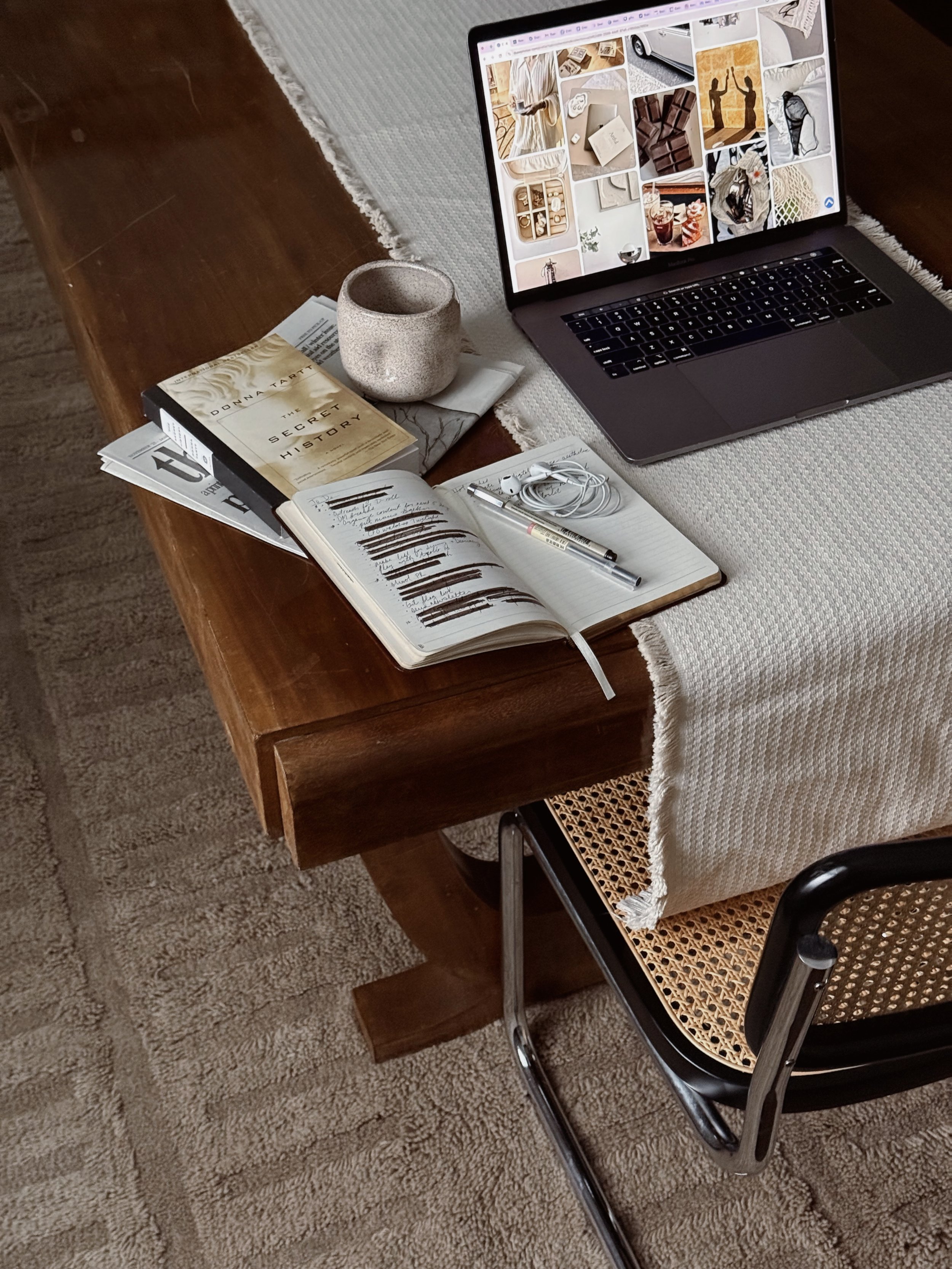 Laptop showing a visual mood board beside a notebook and coffee, representing strategic planning for an eco-conscious brand.