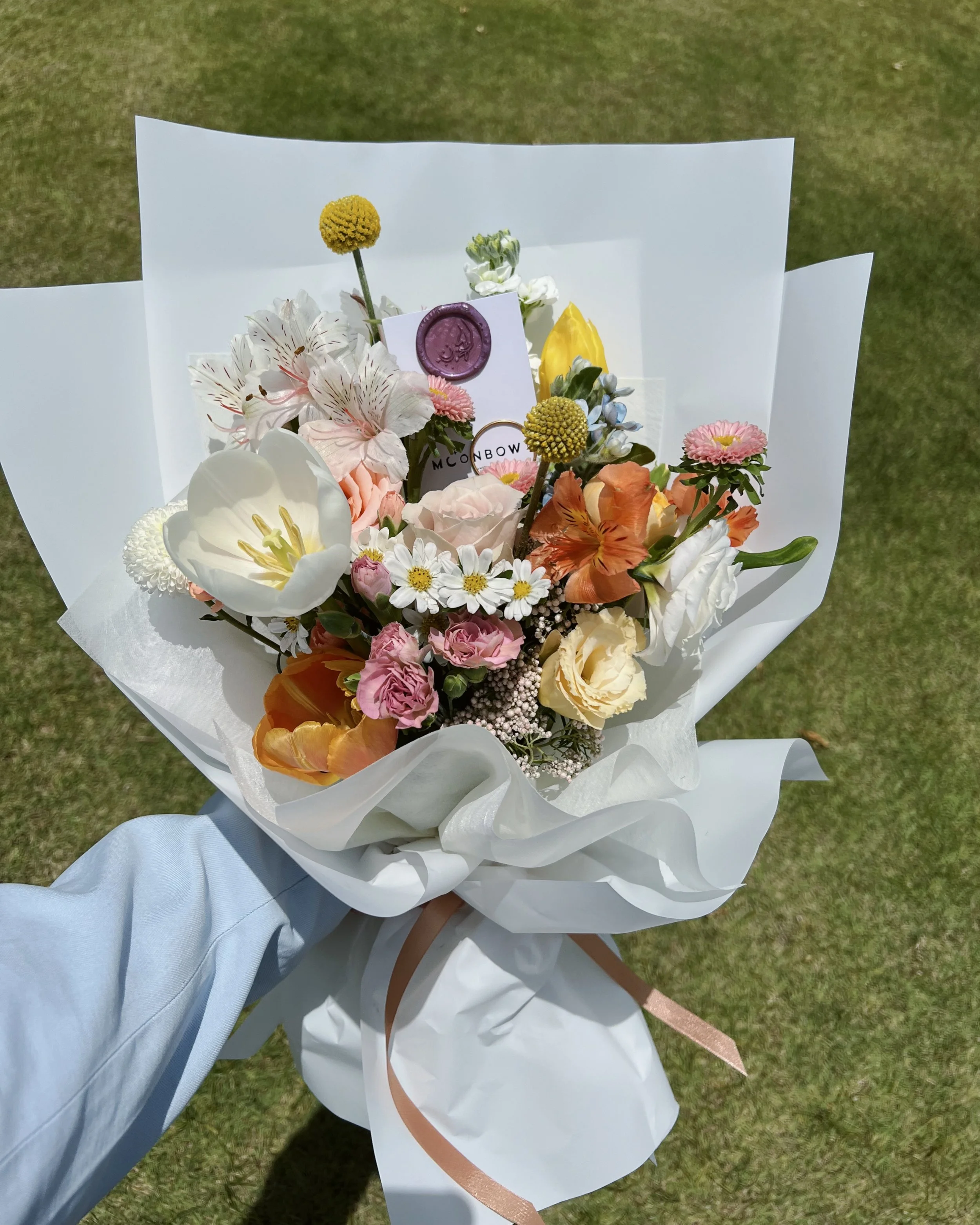 Colourful bouquet of flowers wrapped in paper on grass, representing creative clarity and thoughtful brand support.