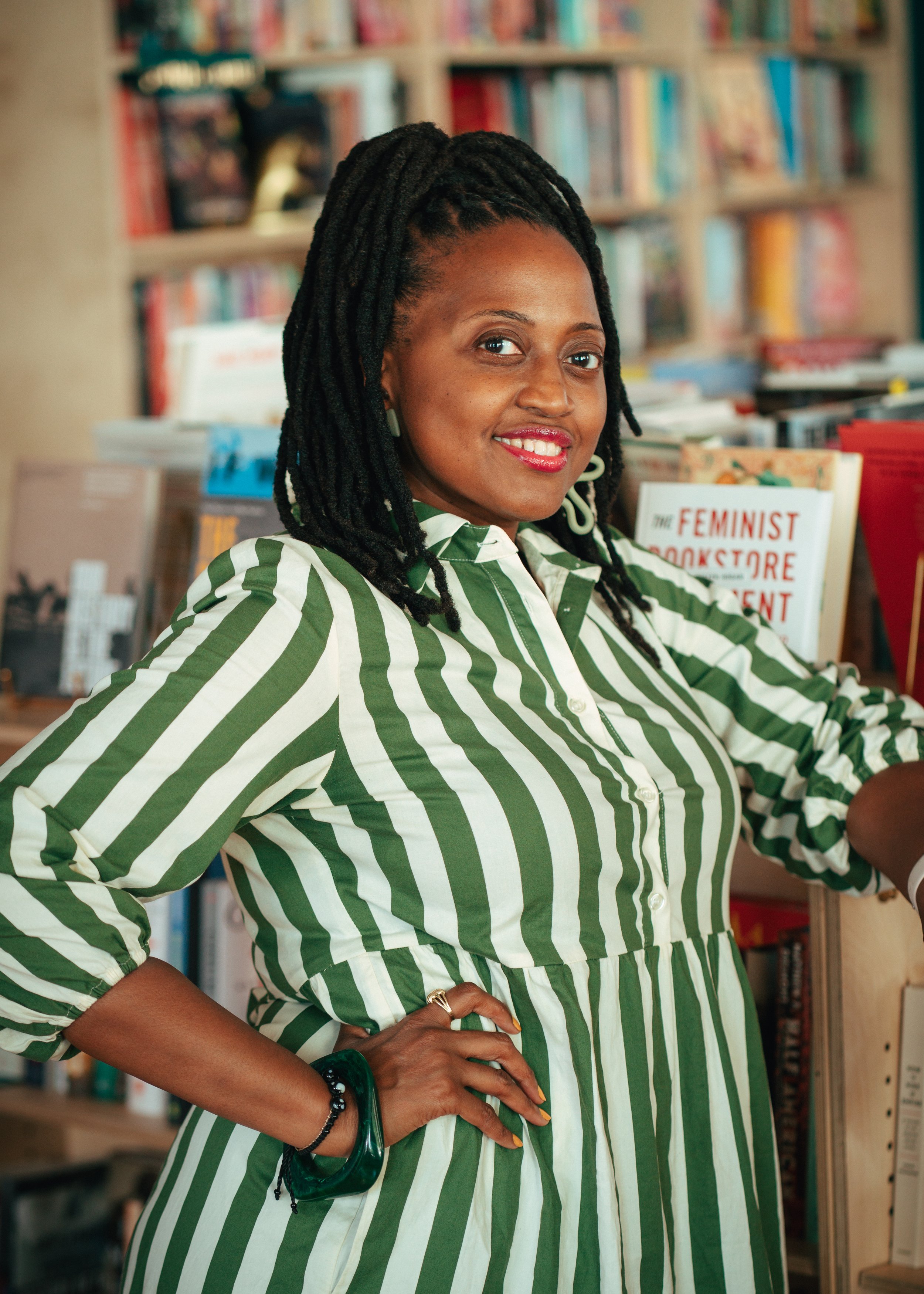 Jacquinn Sinclair in a white and green striped dress in a bookstore