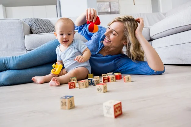 mother-looking-at-baby-boy-playing-with-toys-in-living-room_1170-428 (1).jpg