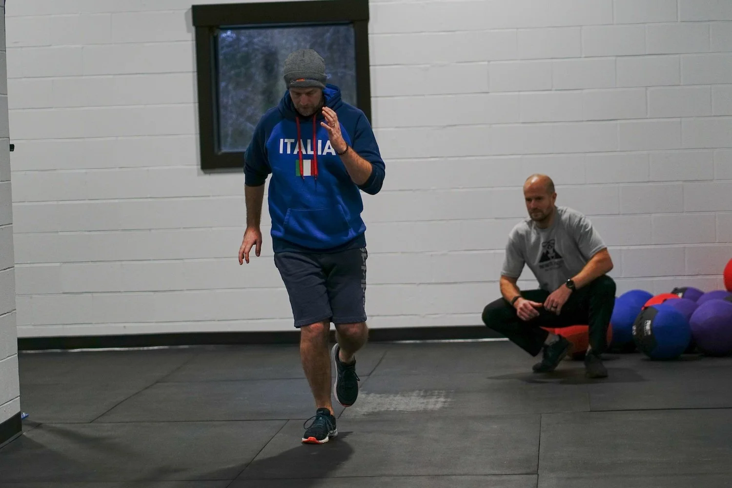 Sports physical therapist watching a running client perform running specific drills to fix their knee pain.