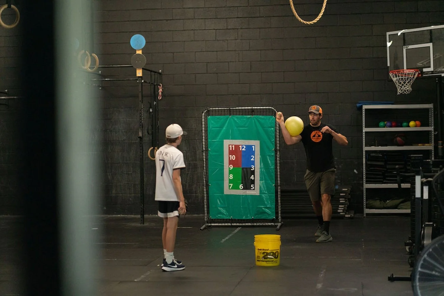 Sports physical therapist demonstrating a baseball pitching drill to a client working on pitching performance.