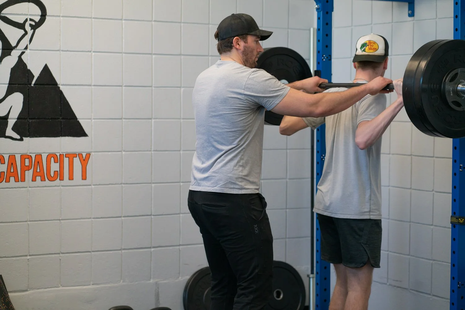 Physical therapist spotting a client back squatting heavy load during a treatment session in South Portland, Maine.