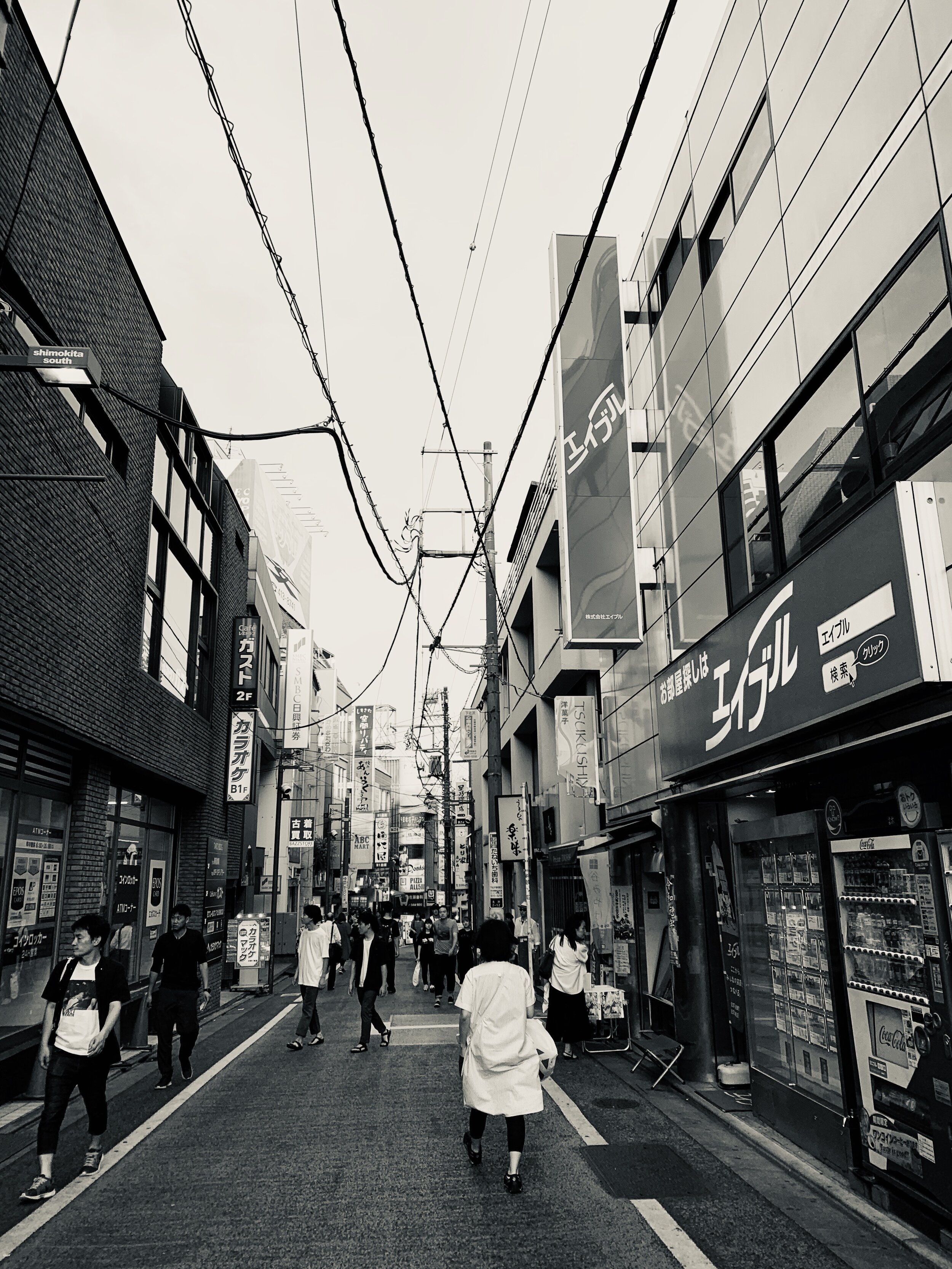  A black and white photo of people walking through a street in a vintage shopping district of Tokyo 