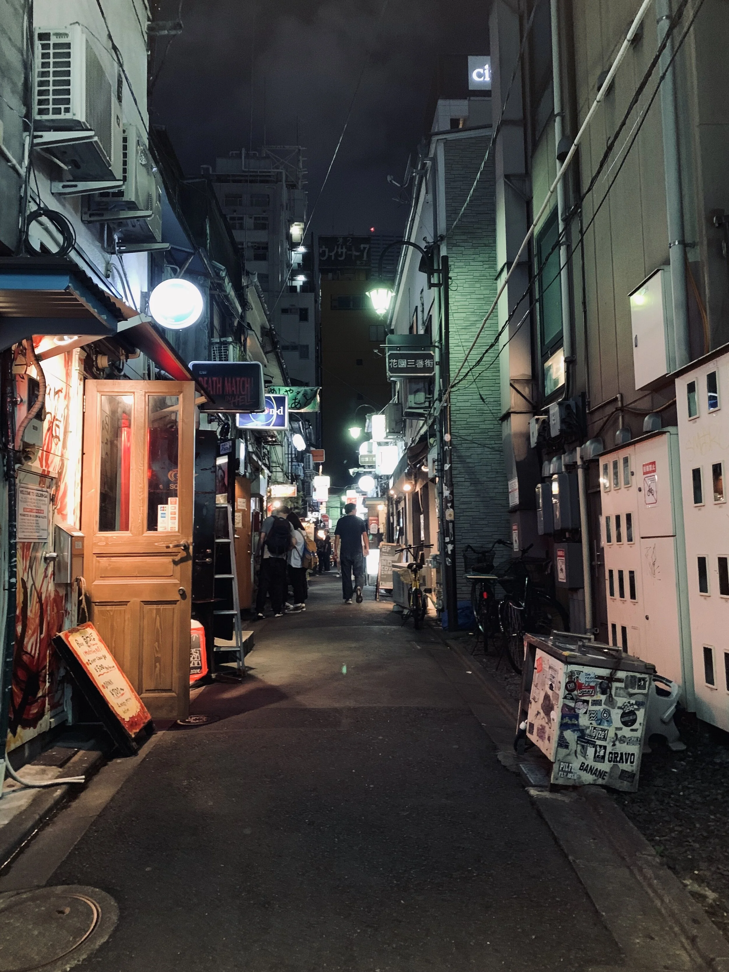 Bright lights twinkle in a narrow side street illuminating a bar door in Tokyo 