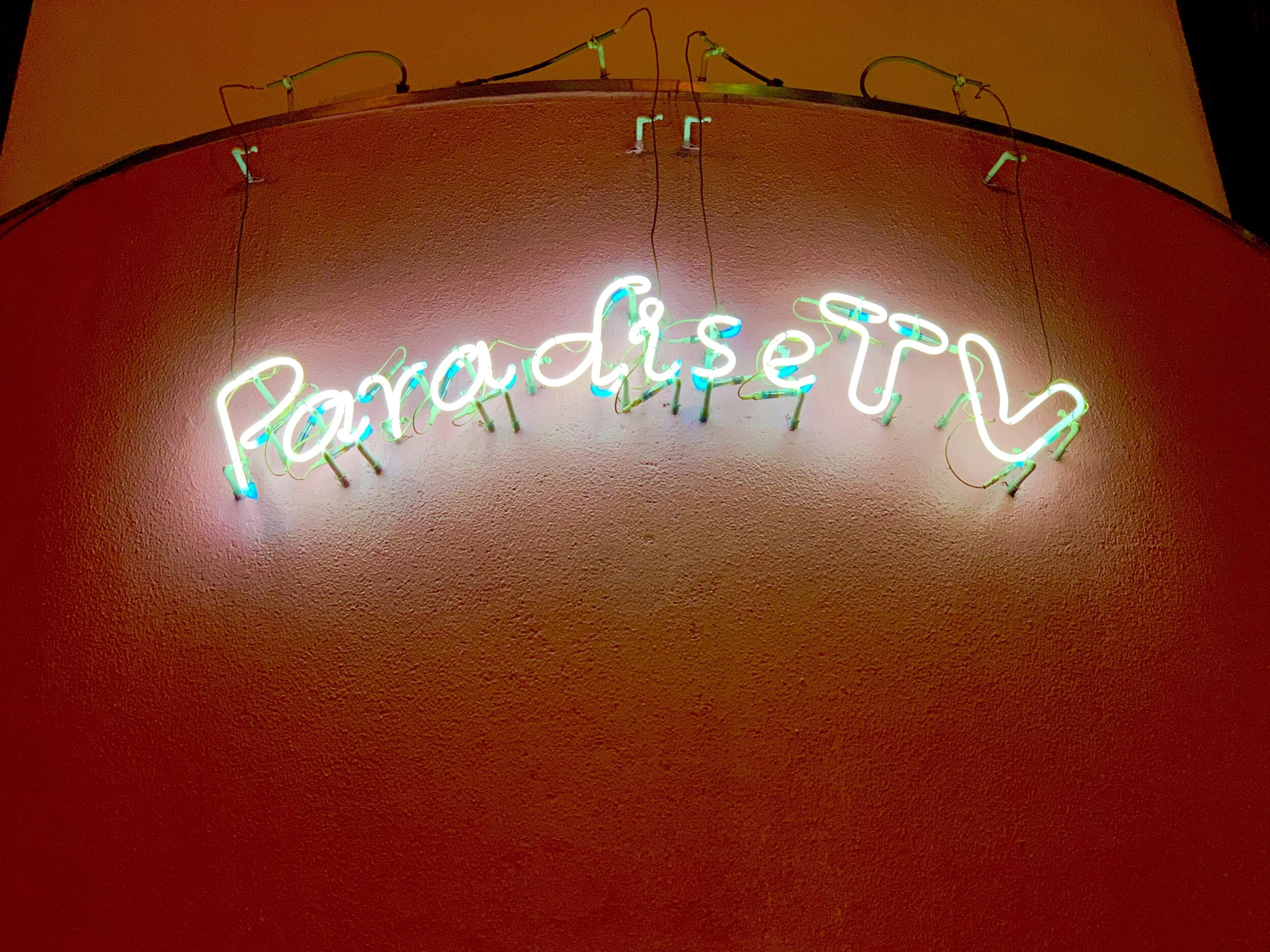  A neon sign of ParadiseTV lights up the side of a peach colored building in Tokyo 