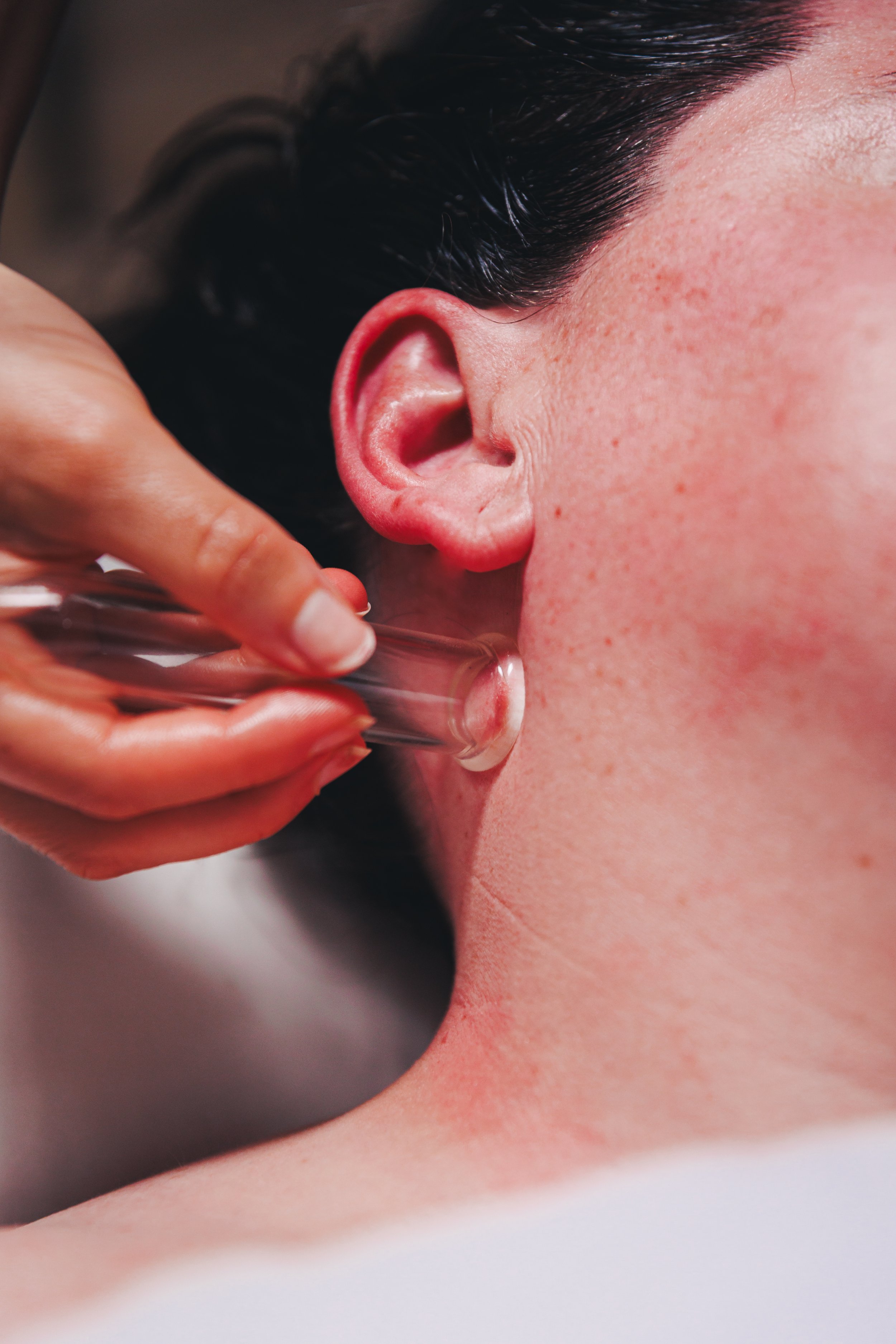 A person receiving an ear cleaning with a glass syringe to remove earwax.