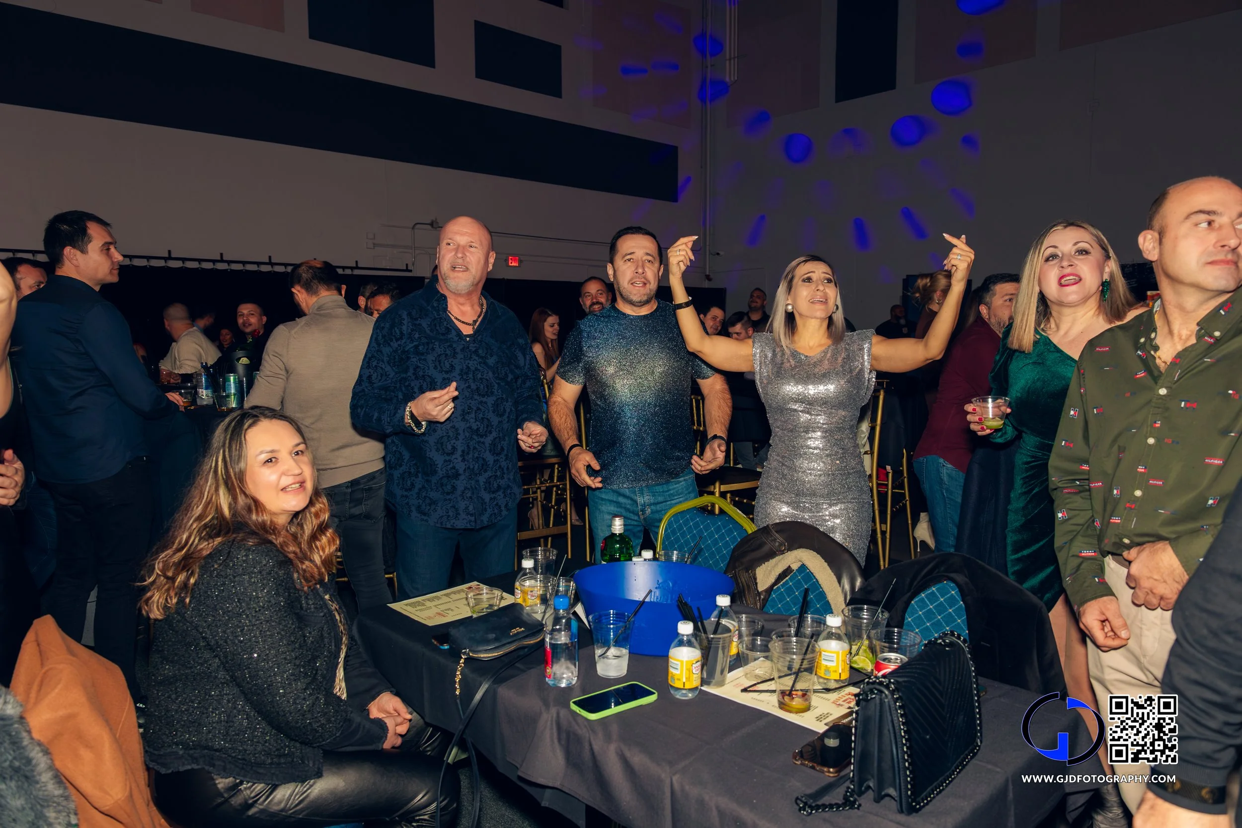 Group of people dancing and socializing at a party or celebration in a decorated indoor venue.